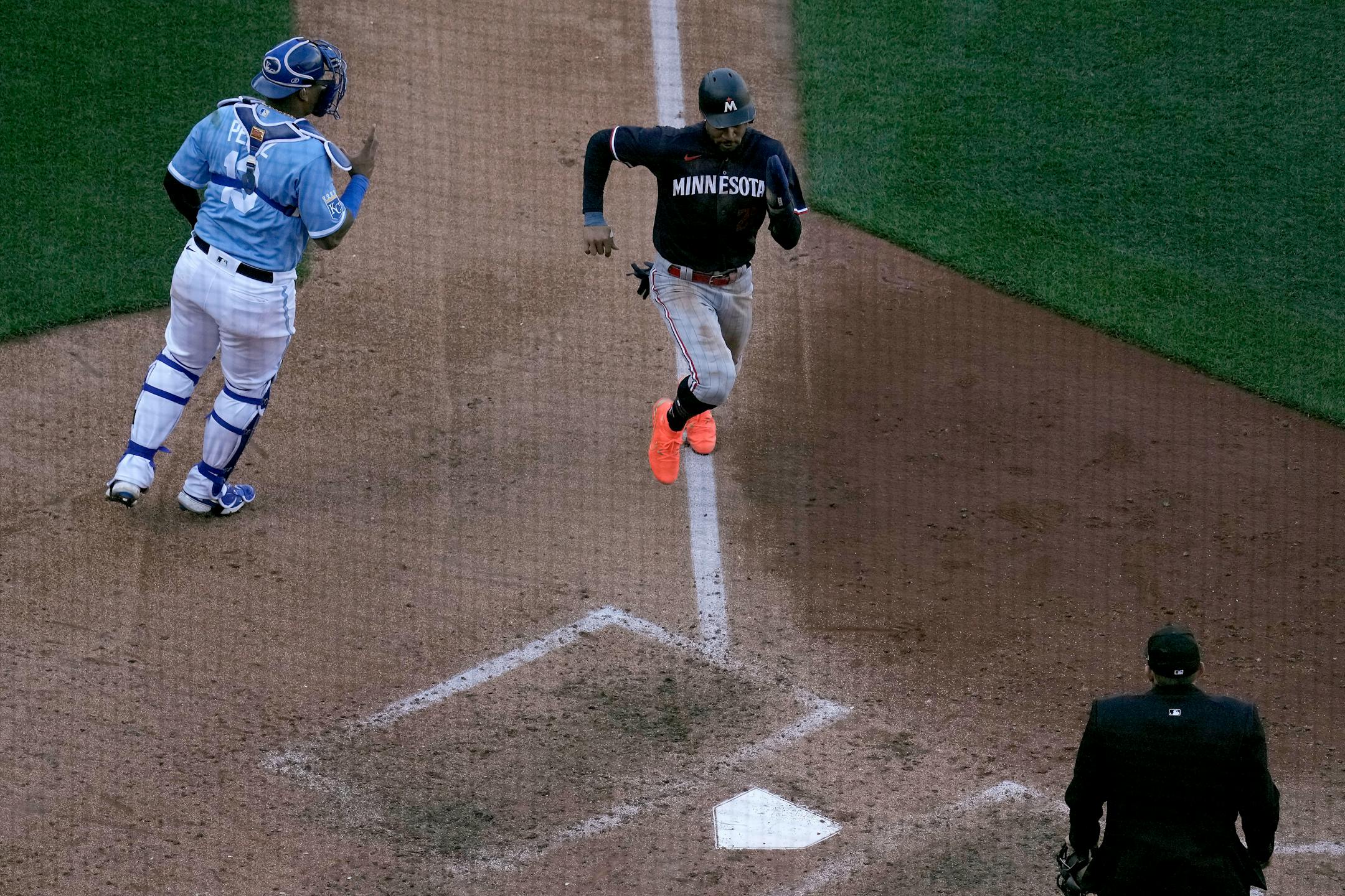 Minnesota Twins' Byron Buxton runs past Kansas City Royals catcher Salvador Perez to score on a sacrifice fly hit by Kyle Farmer during the sixth inning of a baseball game Saturday, April 1, 2023, in Kansas City, Mo. (AP Photo/Charlie Riedel)