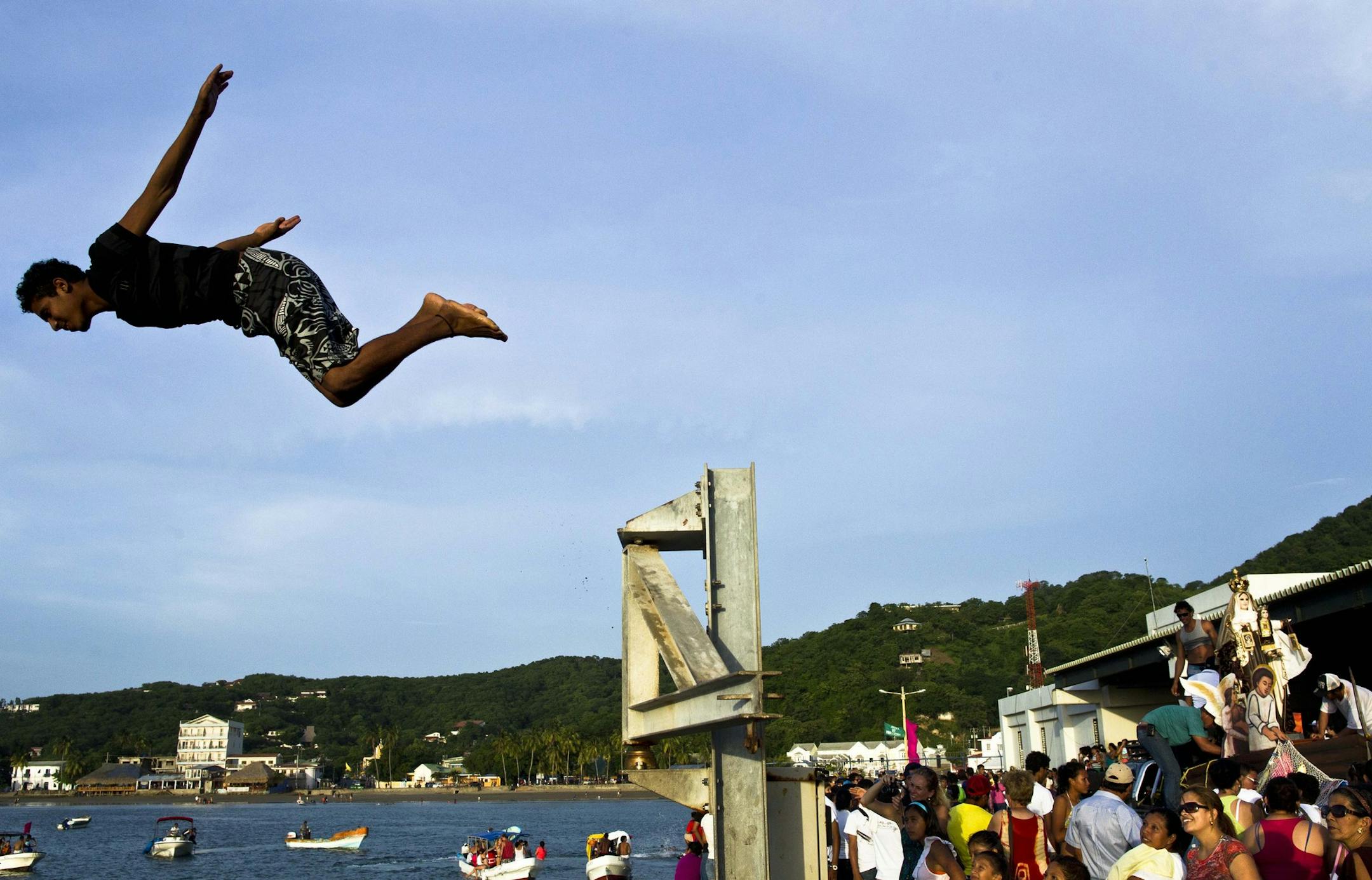 A man jumps into the Pacific Ocean during a religious procession of the Virgin of Carmen, right, at the dock of San Juan del Sur, Nicaragua, Tuesday, July 16, 2013. Nicaragua's fishing community celebrate the feast day of the Virgin of Carmen who is worshipped by Catholics as the patron saint of fishermen and sailors. (AP Photo/Esteban Felix)
