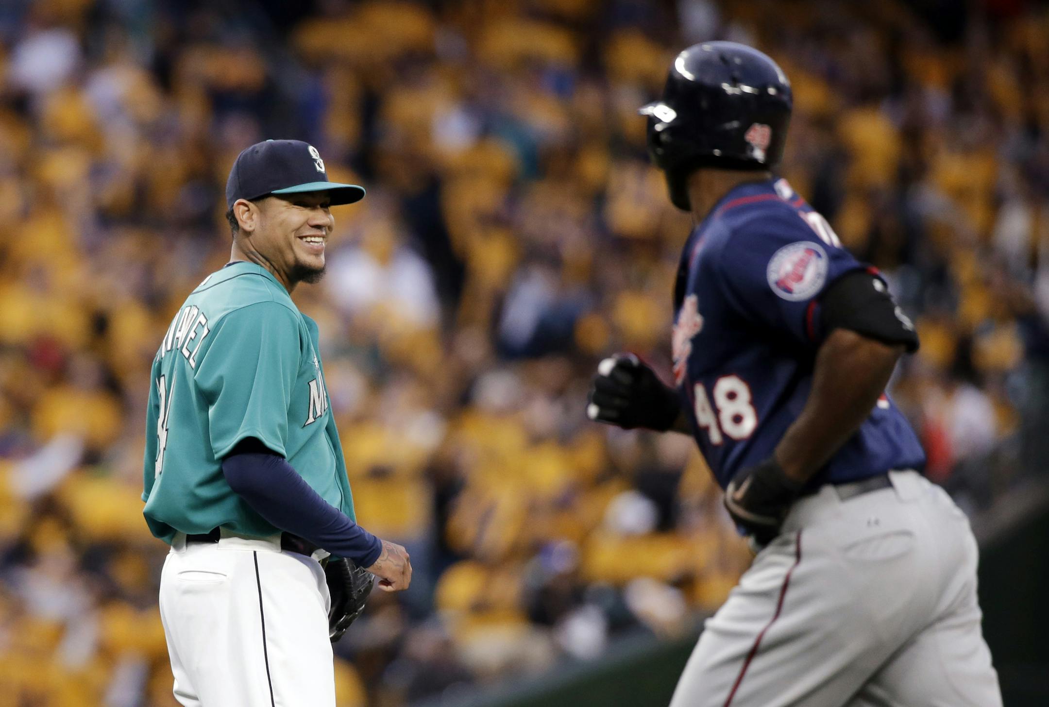 Seattle Mariners starting pitcher Felix Hernandez, left, smiles as he looks across at Minnesota Twins' Torii Hunter as Hunter leaves the field after flying out during the fourth inning of a baseball game Friday, April 24, 2015, in Seattle. (AP Photo/Elaine Thompson)
