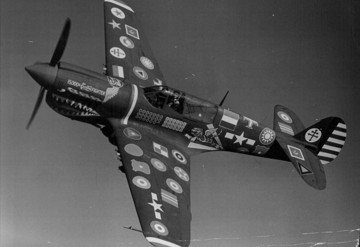 November 24, 1944 Emblazoned with the insignia of all the 28 air forces with which Curtiss fighters have served during World War II, the 15,000th Curtiss fighter (above) rolled off the assembly line at Curtiss-Wright Corporation's Buffalo, N. Y., plant Wednesday, Nov. 22. This plane, Curtiss P-40 War hawk, marked a world's record, Curtiss-Wright having built more fighter" war than any other manufacturer in the world. At the controls for first flights of the 15,000th fighter was Test Pilot H. Llo