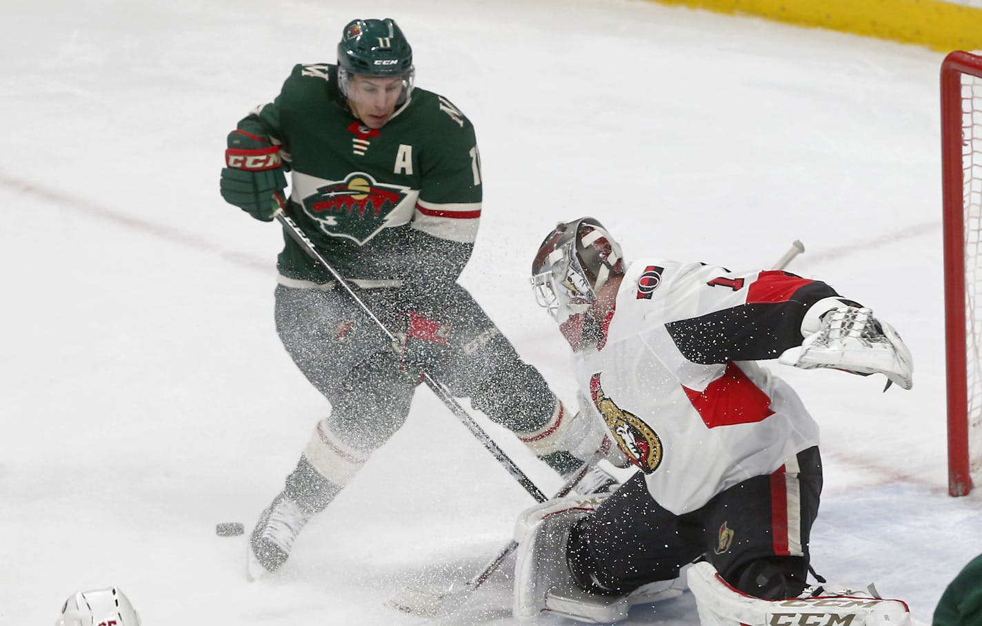 Ottawa Senators goaltender Mike Condon, right, stops a shot as the puck slides under Minnesota Wild's Zach Parise in the second period of an NHL hockey game Monday, Jan. 22, 2018, in St. Paul, Minn. (AP Photo/Jim Mone)