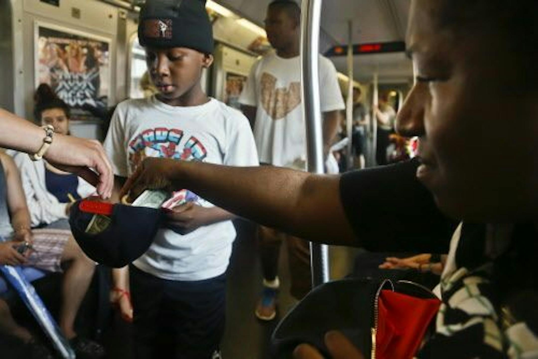 In this June 17, 2014 photo, Marc Mack, 8, a member with the dance troupe W.A.F.F.L.E., which stands for We Are Family For Life Entertainment, collects money from subway riders after a performance in New York.