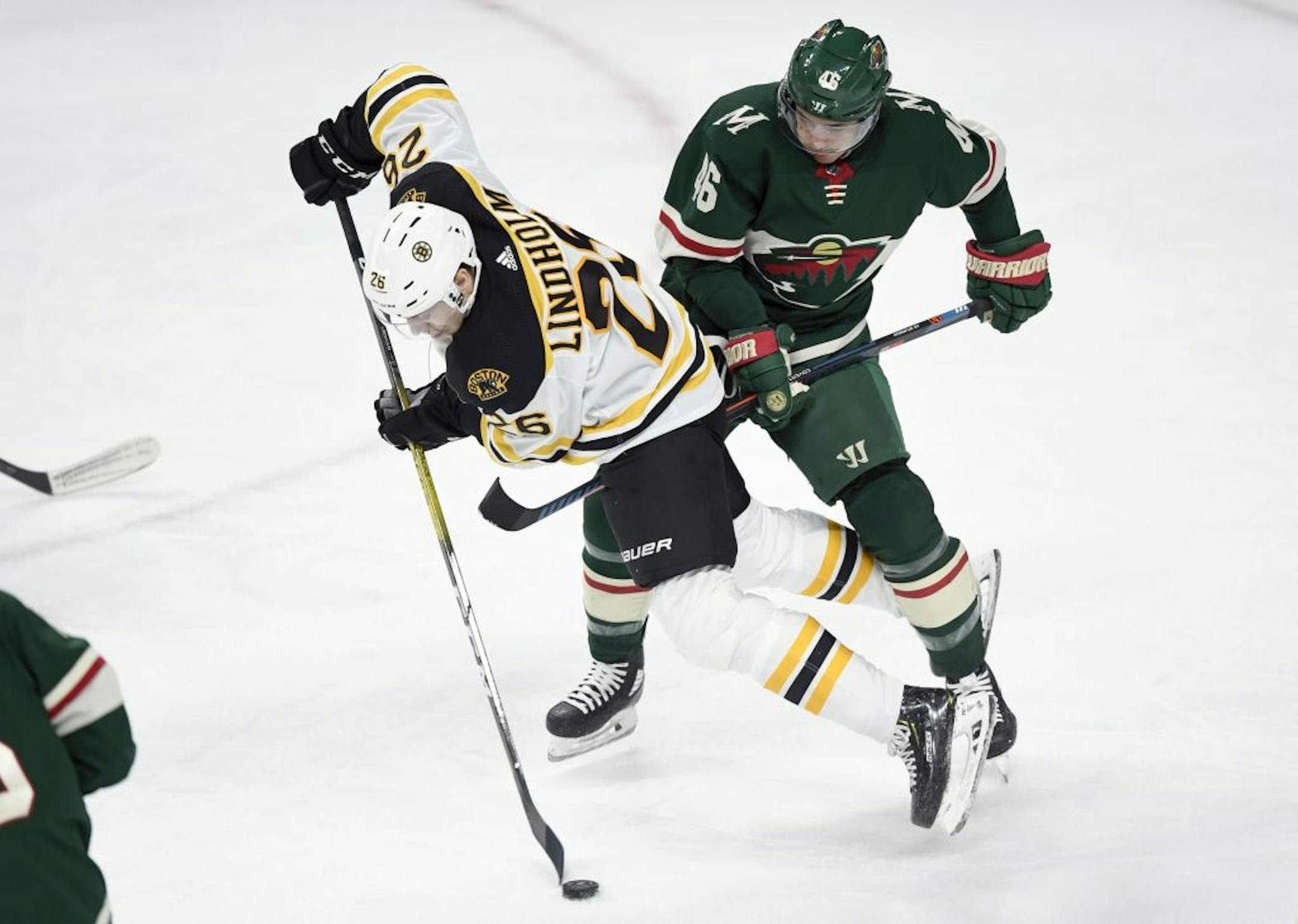Boston Bruins' Par Lindholm (26), of Sweden, has the puck against Minnesota Wild's Jared Spurgeon (46) during the first period of an NHL hockey game Saturday, Feb. 1, 2020, in St. Paul, Minn.
