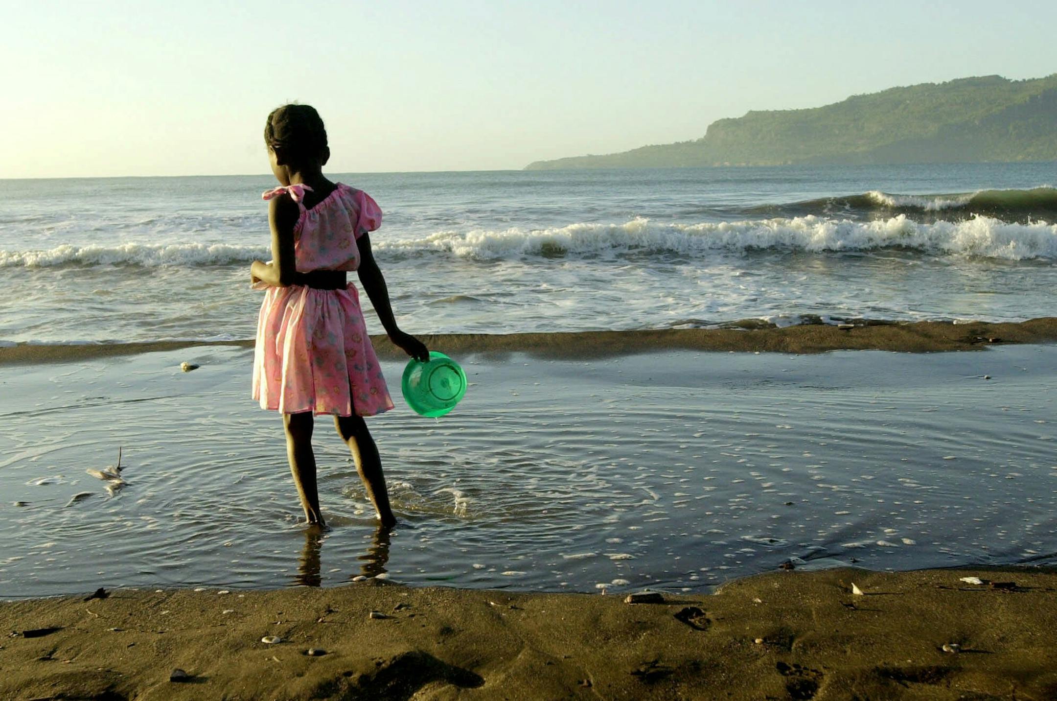 A girl walks on the beach in Jacmel, Haiti, Feb. 5, 2001. Jacmel is a relative paradise with its 24-hour electricity, clean air and a newly-built wharf area the government hopes will someday be filled with tourists and cruiseships. (AP Photo/Lynne Sladky)