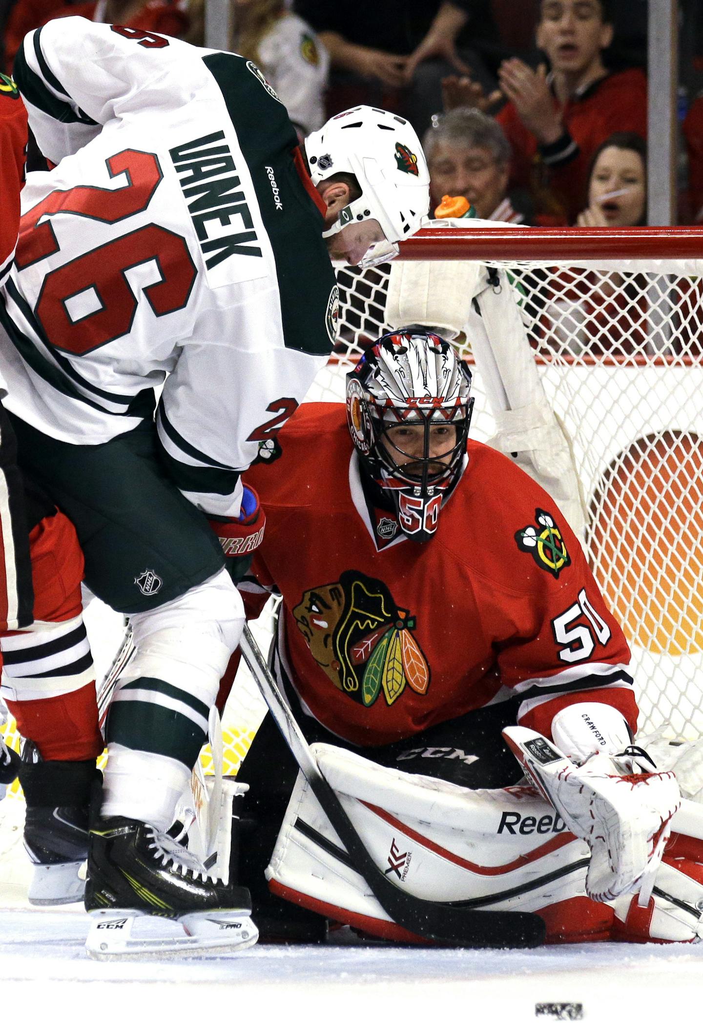 Chicago Blackhawks goalie Corey Crawford, right, blocks ascot by Minnesota Wild left wing Thomas Vanek (26) during the first period of Game 2 in the second round of the NHL Stanley Cup hockey playoffs in Chicago, Sunday, May 3, 2015. (AP Photo/Nam Y. Huh) ORG XMIT: MIN2015050620053828