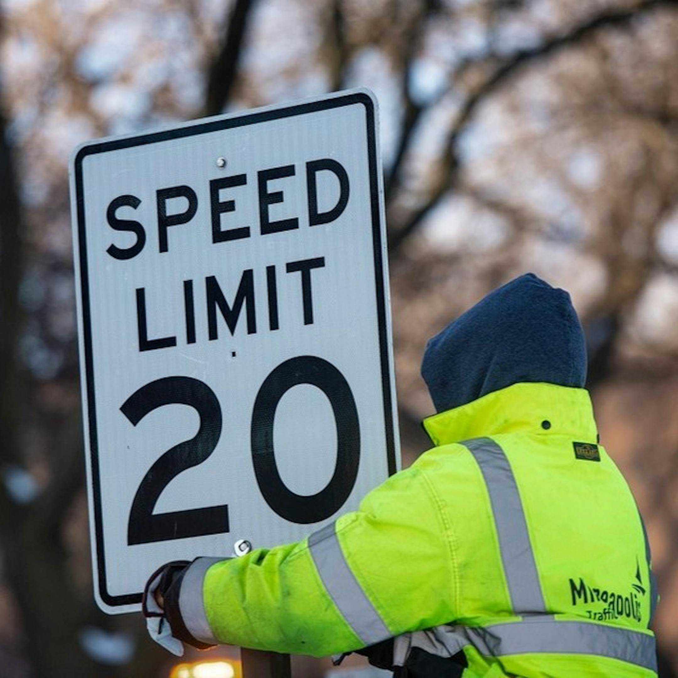 A worker puts up a new speed limit sign on Kenwood Parkway in Minneapolis.
