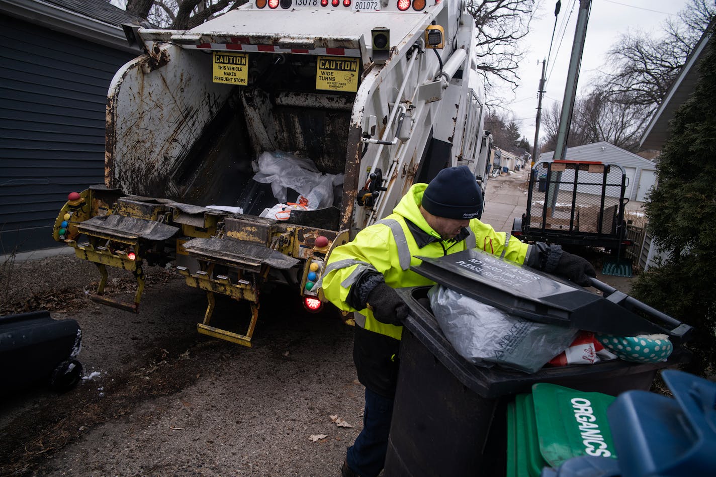 Sanitation worker David Kutzbach does the garbage pickup in an alley in the Nokomis area in Minneapolis, Minn., on Wednesday, Jan. 3, 2024. But while some parts of a household budget are trimmable, others are not — and those prices keep going up (think: health insurance, car insurance, utilities). ] RICHARD TSONG-TAATARII • richard.tsong-taatarii @startribune.com