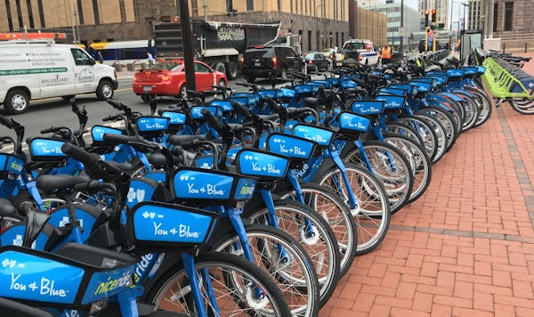 Nice Ride Minnesota offers by bike-sharing in Minneapolis with blue dockless bikes and green bikes parked at docking stations.
