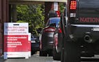 Cars idle in line as patients wait to self-take a COVID-19 virus test at a drive thru for the CVS Pharmacy in Danvers, Mass., Friday, May 15, 2020. CV