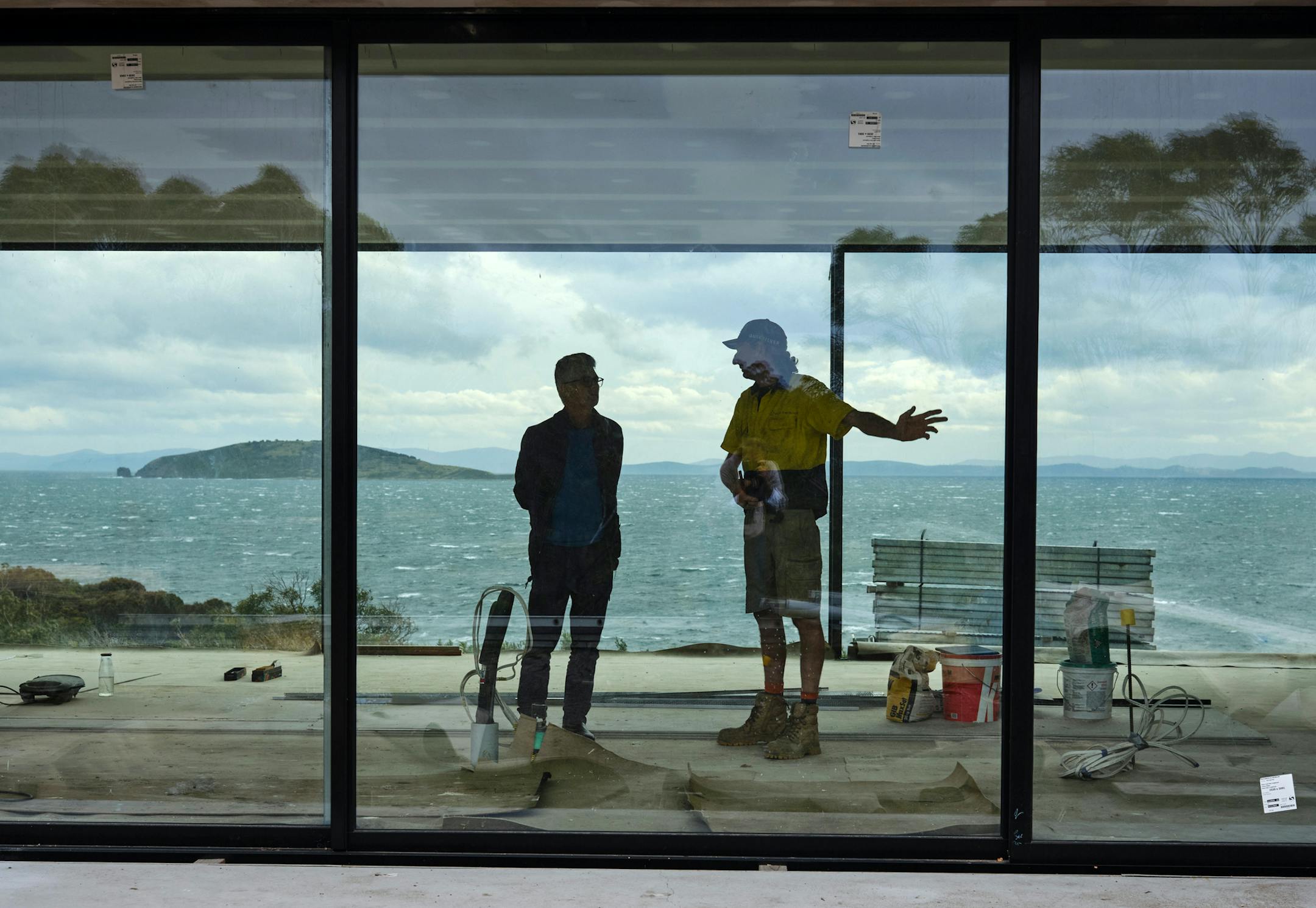 Architect Ian Weir, left, talks with builder Shane Salter about progress on the Apex Point House, which Weir designed with steel cladding to keep out stray embers, in White Beach, Australia, Feb. 27, 2020. As the country rebuilds after its devastating wildfires, Weir is leading a push to integrate houses with the land rather than mass clearance of vegetation. (Alana Holmberg/The New York Times)
