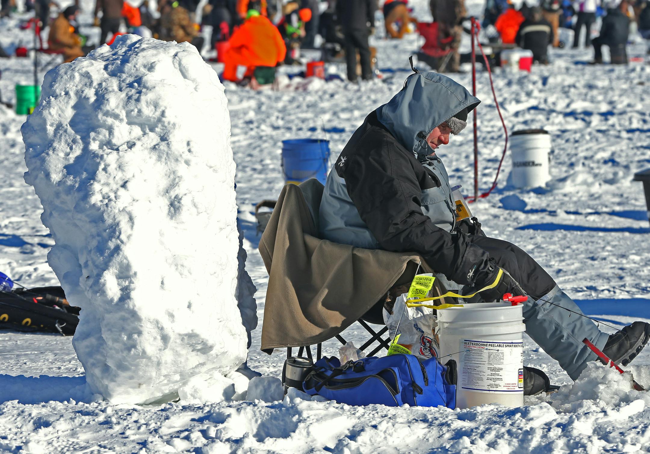 Jeff Leibold of Spring Valley MN., huddled behind a large chunk of snow, trying to get out of the wind. Leibold was amoung the 10,000 anglers from the midwest and Minnesota who took part in the 24th annual Brainerd Jaycees $150,000 Ice Fishing Extravaganza on Gull Lake's Hole in the Day Bay. This year marks the 21st time Bretsch has taken part in the contest. The fishermen competed for over $200,000 in prizes and all proceeds benefited area charities.] Bruce Bisping/Star Tribune bbisping@startri