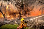 Firefighter Christian Moorhouse battles the Park Fire tears though the Cohasset community in Butte County, Calif., on Thursday, July 25, 2024. His cre