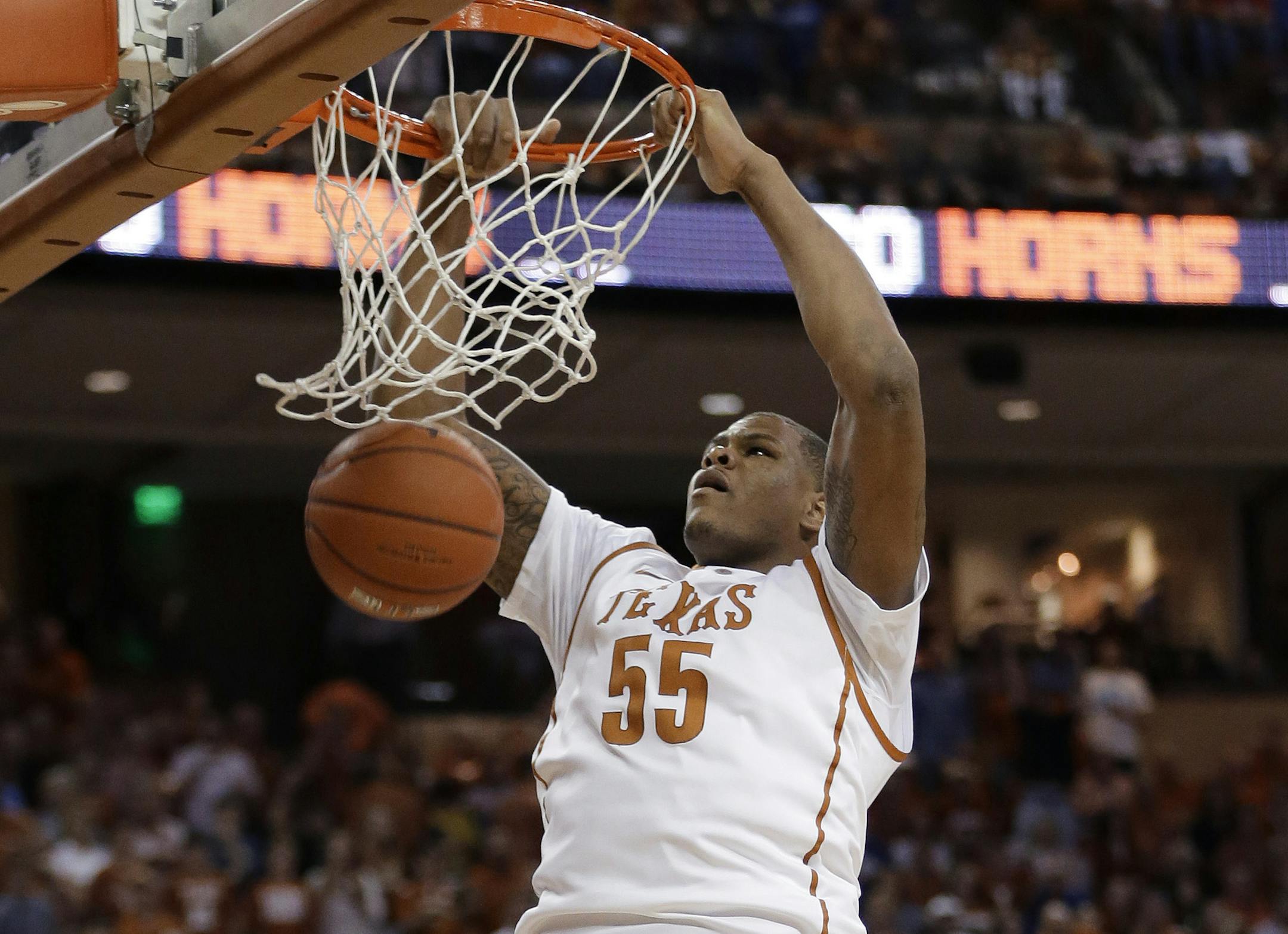 Texas' Cameron Ridley (55) scores over Kansas' Perry Ellis (34) and Joel Embiid (21) during the first half of an NCAA college basketball game, Saturday, Feb. 1, 2014, in Austin, Texas. (AP Photo/Eric Gay)