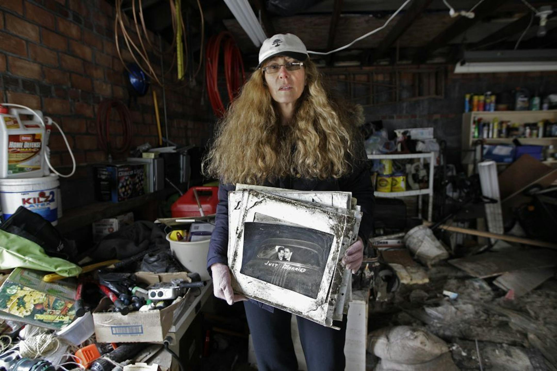 In this photo taken Nov. 19, 2012, Roseanne Schnoll holds her parents' wedding album, a keepsake item she recovered from workers were cleaning out her flooded basement and garage in the Belle Harbor neighborhood New York. Scholl's house is only yards from the Atlantic Ocean.