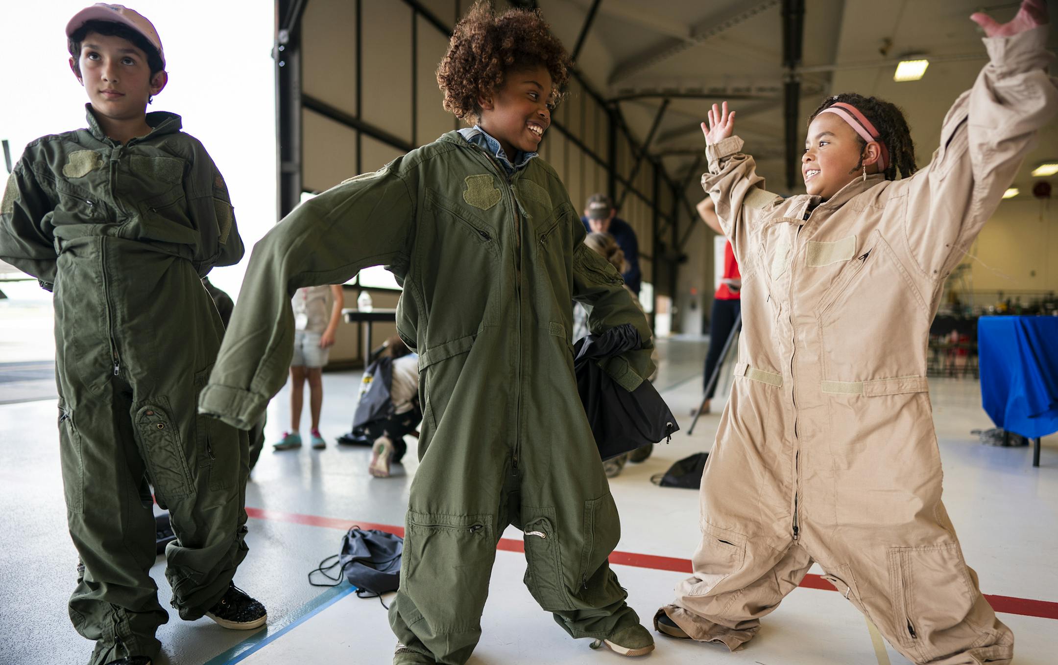 Keegan Campos, from left, 9, Janiah Jordan, 9, and Ava Dawolo, 7, tried on flight suits. ] LEILA NAVIDI • leila.navidi@startribune.com BACKGROUND INFORMATION: Project Scientist: Summer STEM Academy for Girls camp participants visit the Minnesota Air National Guard Aviation Facility to experience Chinook and Blackhawk helicopters and learn about aviation at the St. Paul Downtown Airport on Wednesday, August 7, 2019.