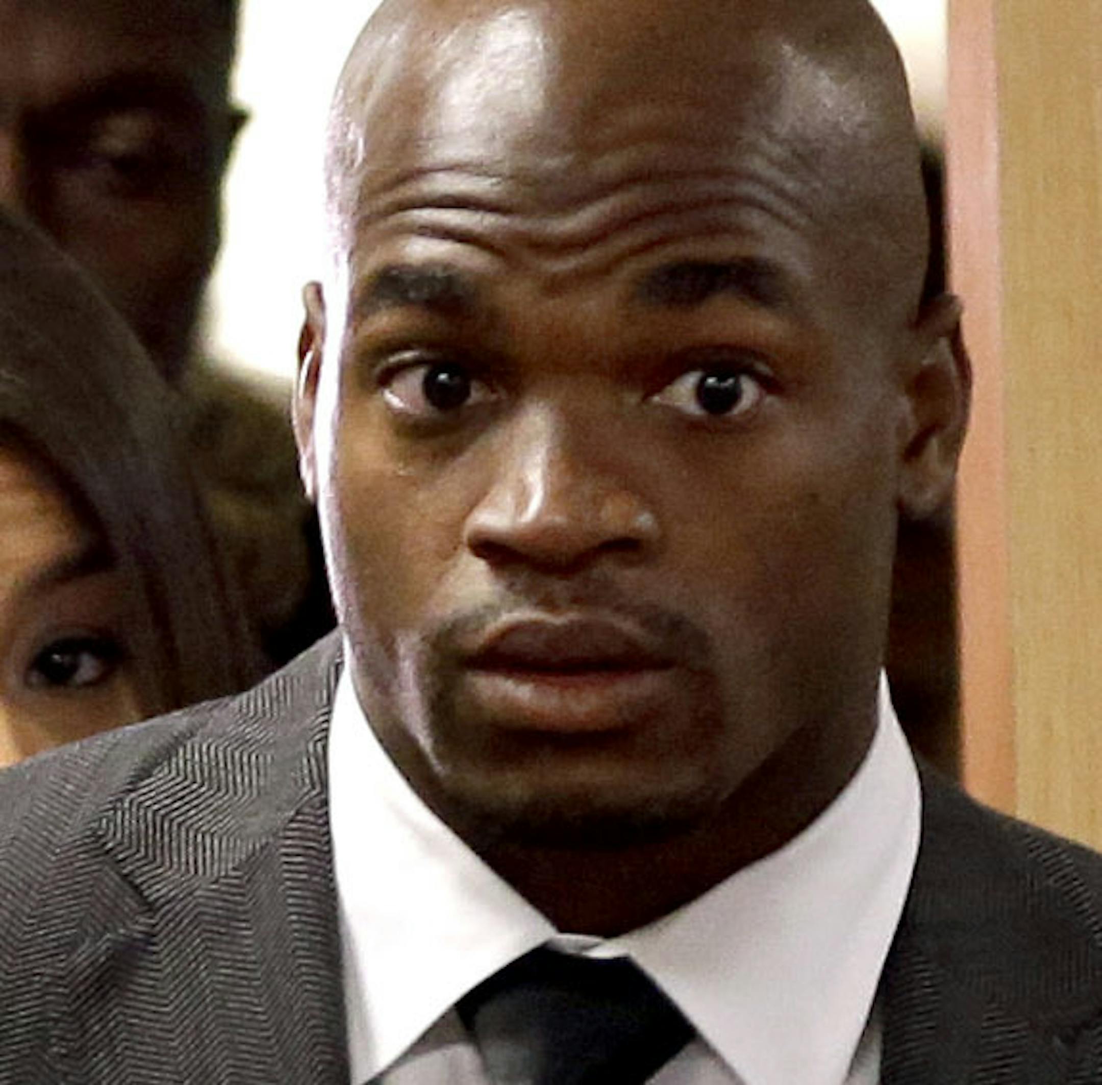 Minnesota Vikings running back Adrian Peterson, center, arrives with his attorney Rusty Hardin, right, for his first court appearance Wednesday, Oct. 8, 2014, in Conroe, Texas. A Texas judge has tentatively set a Dec. 1 trial date for Peterson on a charge of felony child abuse for using a wooden switch to discipline his 4-year-old son. (AP Photo/David J. Phillip, Pool)