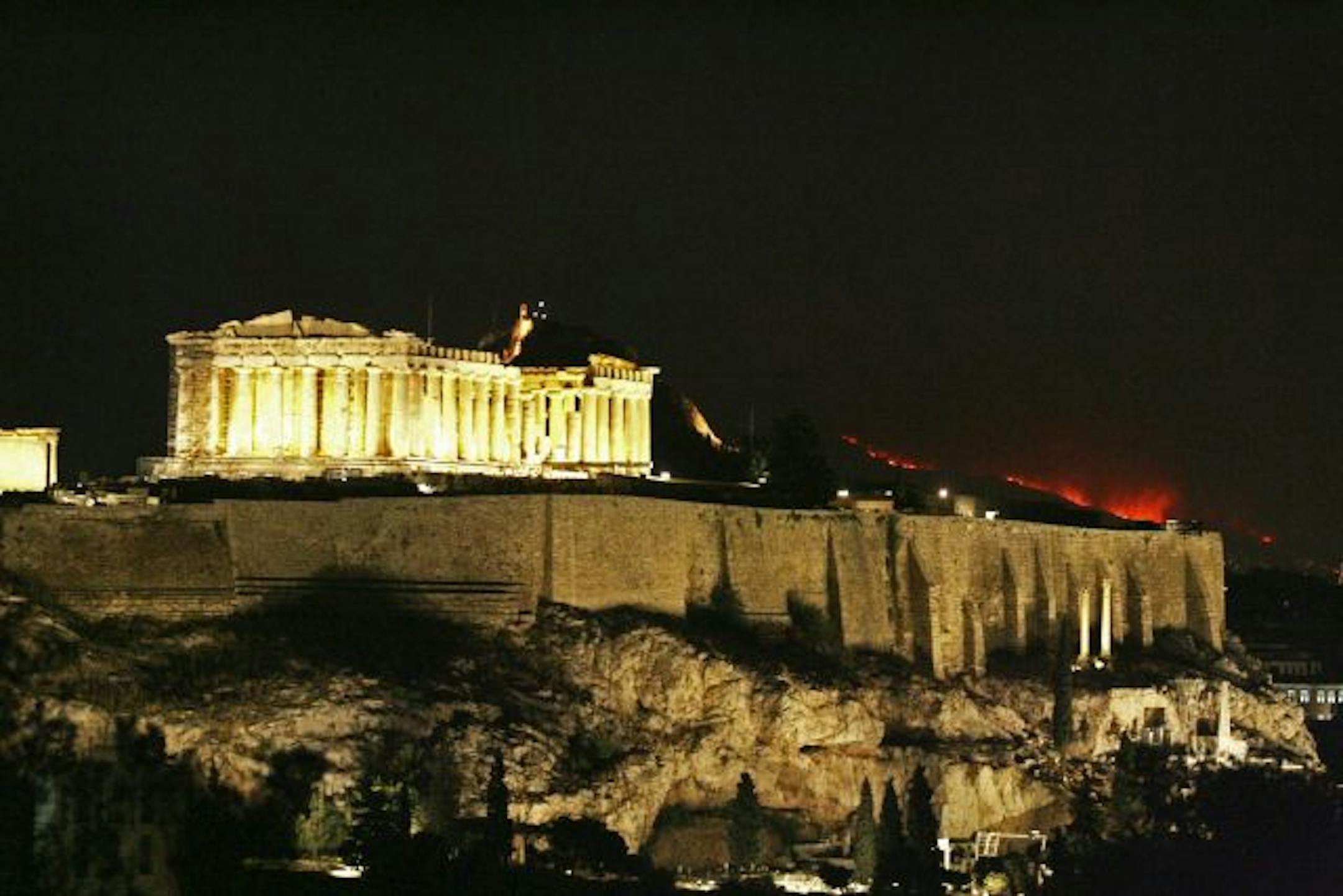 Fires burn on the suburban hills behind the ancient Parthenon at Acropolis in Athens, Greece. A massive wildfire tore through outlying suburbs north of Athens early Sunday, destroying homes and forcing thousands to flee in dramatic overnight evacuations.