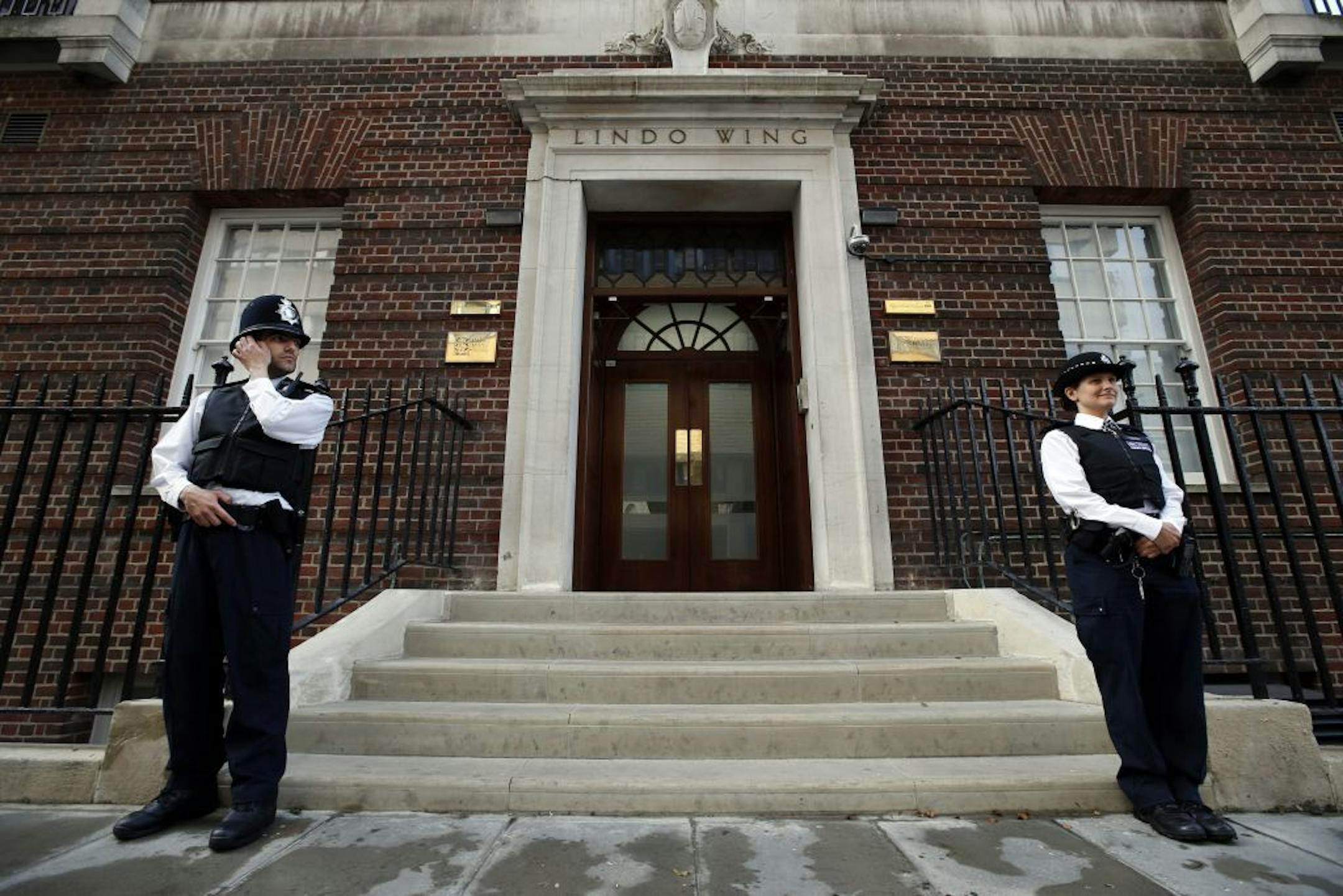 British police officers guard the entrance of St. Mary's Hospital exclusive Lindo Wing in London, Monday, July 22, 2013. Buckingham Palace officials say Prince William's wife, Kate, has been admitted to the hospital in the early stages of labour. Royal officials said that Kate traveled by car to St. Mary's Hospital in central London. Kate _ also known as the Duchess of Cambridge _ is expected to give birth in the private Lindo Wing of the hospital, where Princess Diana gave birth to William and