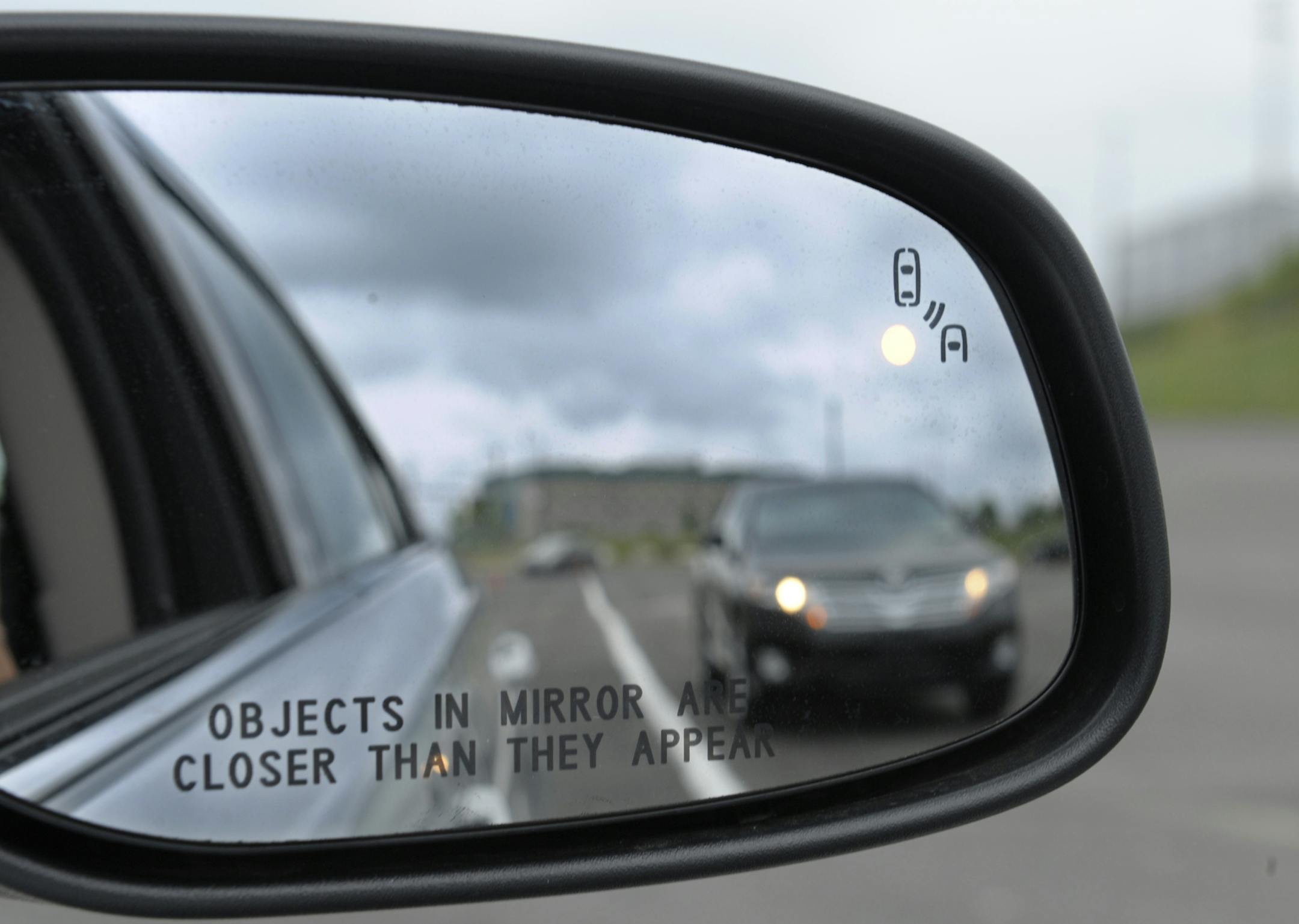 FILE - This May 22, 2012 file photo shows a side mirror warning signal in a Ford Taurus at an automobile testing area in Oxon Hill, Md. Federal officials are planning to announce Monday whether automakers should be required to equip new cars and light trucks with technology that enables vehicles to communicate with each other to prevent collisions. Such vehicle-to-vehicle communication could eventually transform traffic safety. (AP Photo/Susan Walsh, File)