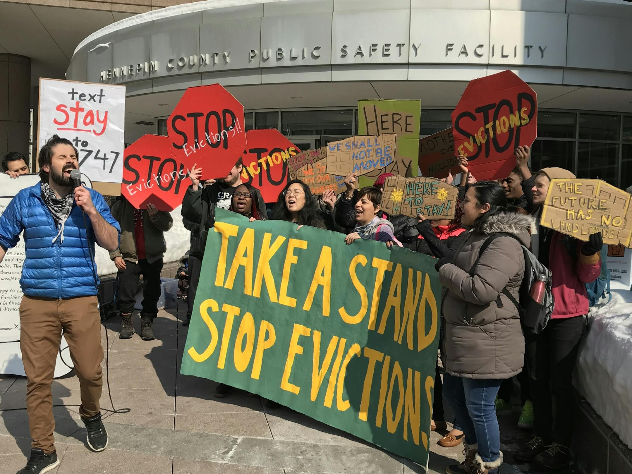 Tenants organizer Roberto de la Riva of United Renters for Justice leads tenants of landlord Stephen Frenz in a chant outside the Hennepin County Public Safety Facility, where Frenz made his first court appearance on felony perjury charges. (Photo by Randy Furst)