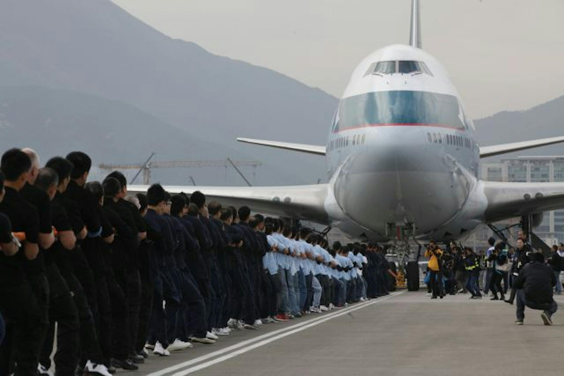A team comprising of staffs of disciplinary forces working at the airport, pull a Boeing B-747 aircraft forward for 100 meters in Hong Kong Airport Thursday, March 17, 2011. The Civil Aviation Department and the aviation industry jointly organized an aircraft pull event to celebrate the 100th anniversary of aviation development in Hong Kong.