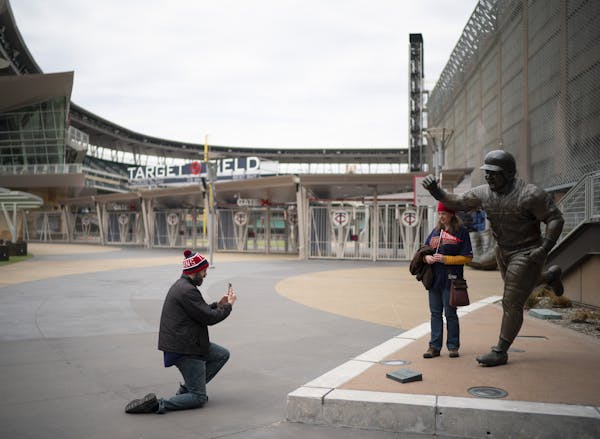 Michele Schluender posed next to the statue of Kirby Puckett before being photographed by her husband, Joe, on the plaza outside Target Field at a tim