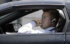 A driver, in compliance with the new California law requiring the use of hands-free mobile phone devices, wears a hands-free device while waiting at a