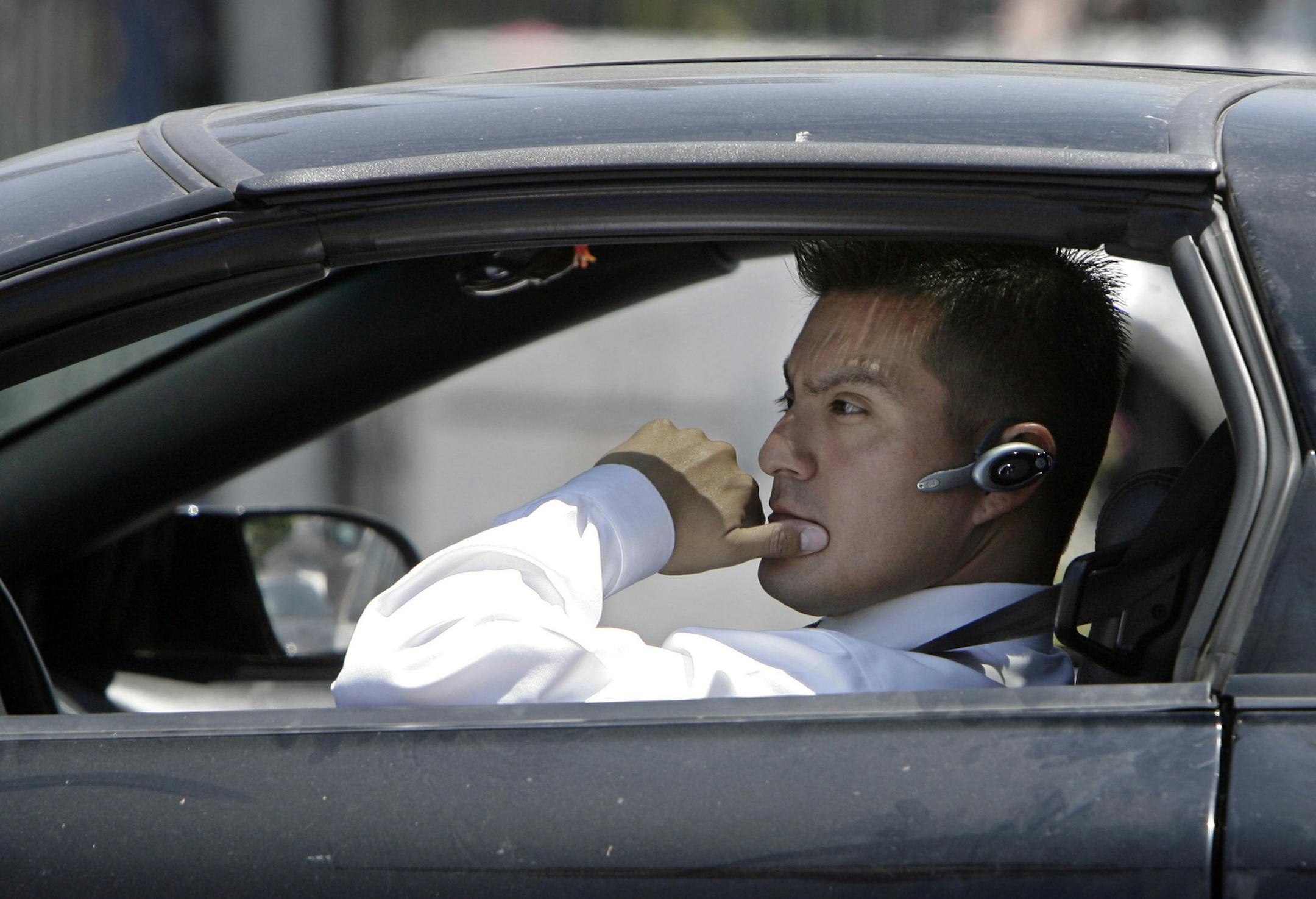 A driver, in compliance with the new California law requiring the use of hands-free mobile phone devices, wears a hands-free device while waiting at a red light Tuesday, July 1, 2008, in Los Angeles. Using a handheld mobile phone while driving became illegal in California on Tuesday. (AP Photo/Ric Francis) ORG XMIT: CARF106