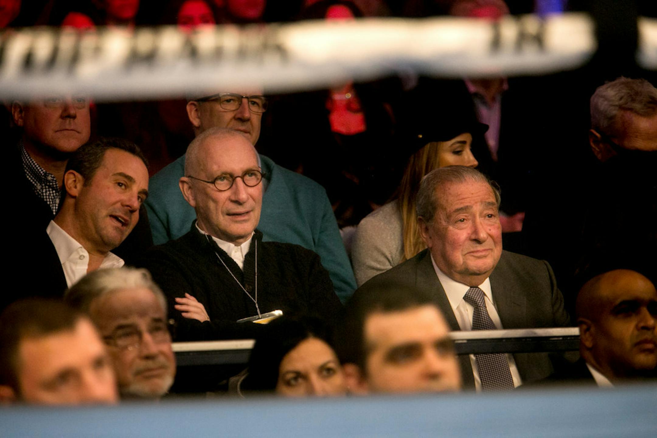 ESPN President John Skipper, in glasses, sits between Todd duBoef, left, and Bob Arum, right, of Top Rank as they watch the fight between Guillermo Rigondeaux and Vasyl Lomachenko at the Theater at Madison Square Garden in New York, Dec. 9, 2017.