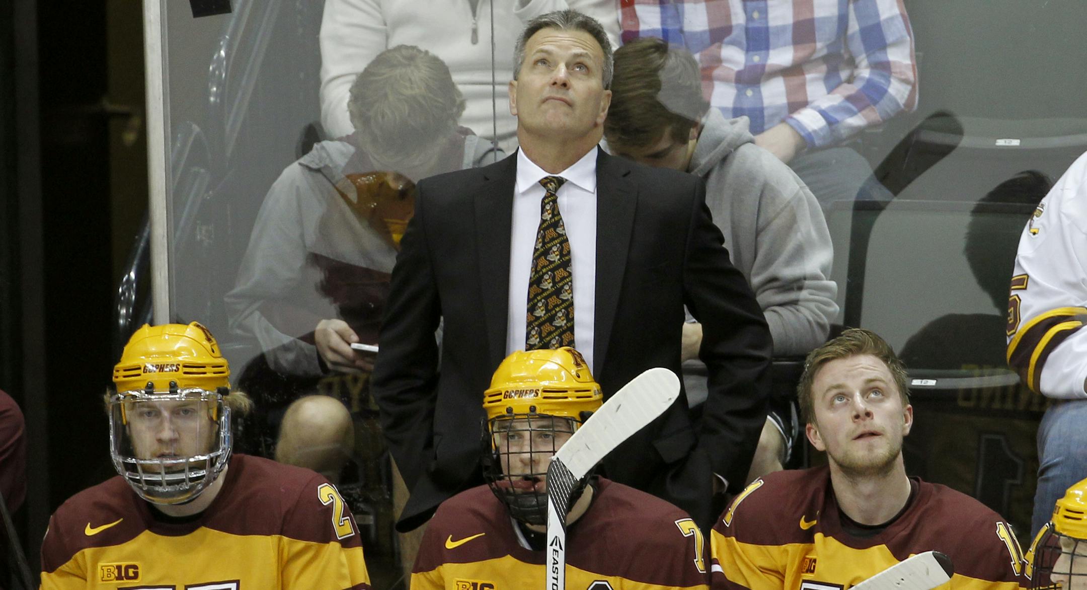 Minnesota head coach Don Lucia, top, checks the scoreboard during the first period of an NCAA West college regional hockey game against St. Cloud State in St. Paul, Minn., Sunday, March 30, 2014. (AP Photo/Ann Heisenfelt)
