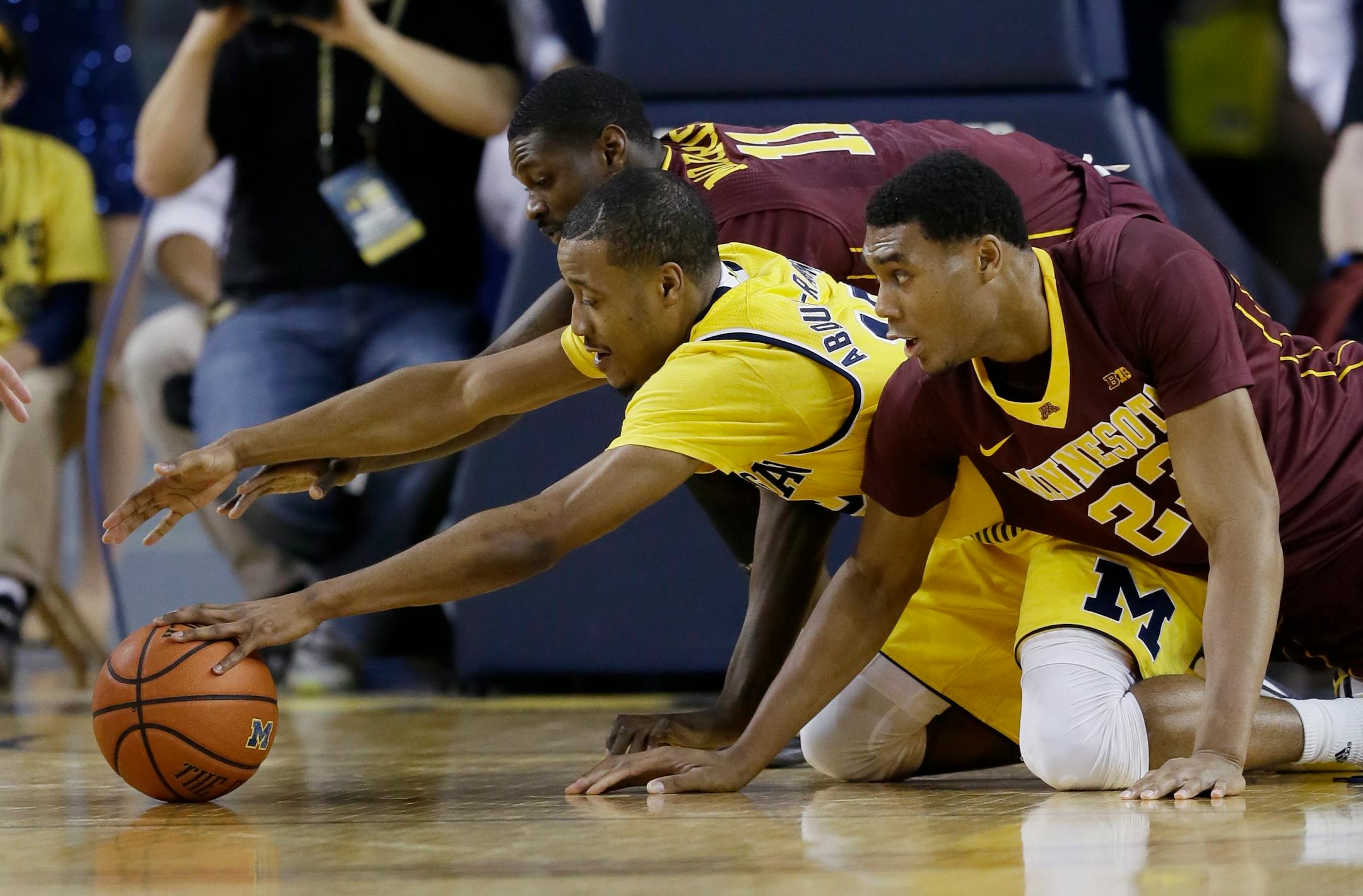Michigan guard Muhammad-Ali Abdur-Rahkman (12), Minnesota guard Carlos Morris (11) and Minnesota forward Charles Buggs (23) fight for the loose ball during the first half of an NCAA college basketball game, Wednesday, Jan. 20, 2016 in Ann Arbor, Mich. (AP Photo/Carlos Osorio)