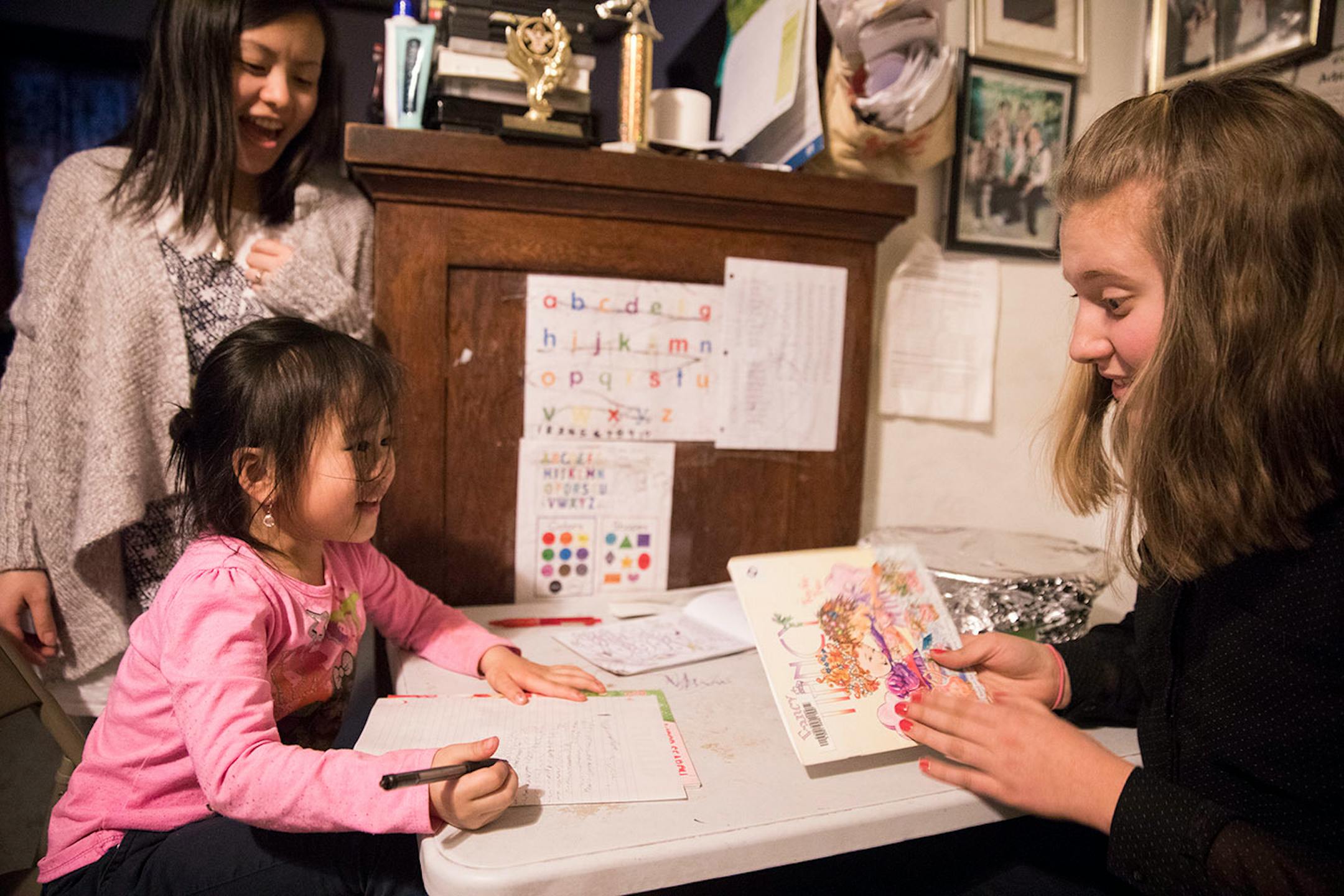 Minnehaha Academy student Abbi Slininger, right, 15, reads a bedtime book with Jane Lee, 5, as her aunt Jewelly Lee looks on.] LEILA NAVIDI ï leila.navidi@startribune.com BACKGROUND INFORMATION: in St Paul on Wednesday, March 15, 2017. City Stay is an opportunity for Minnesota high school students to do home stays at the homes of other local residents. The cultural exchange program fosters new relationships among Minnesota's European, Latin American, Somali and Hmong communities.