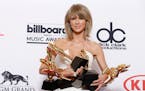 Taylor Swift poses in the press room with the awards for top Billboard 200 album for "1989", top female artist, chart achievement, top artist, top Bil