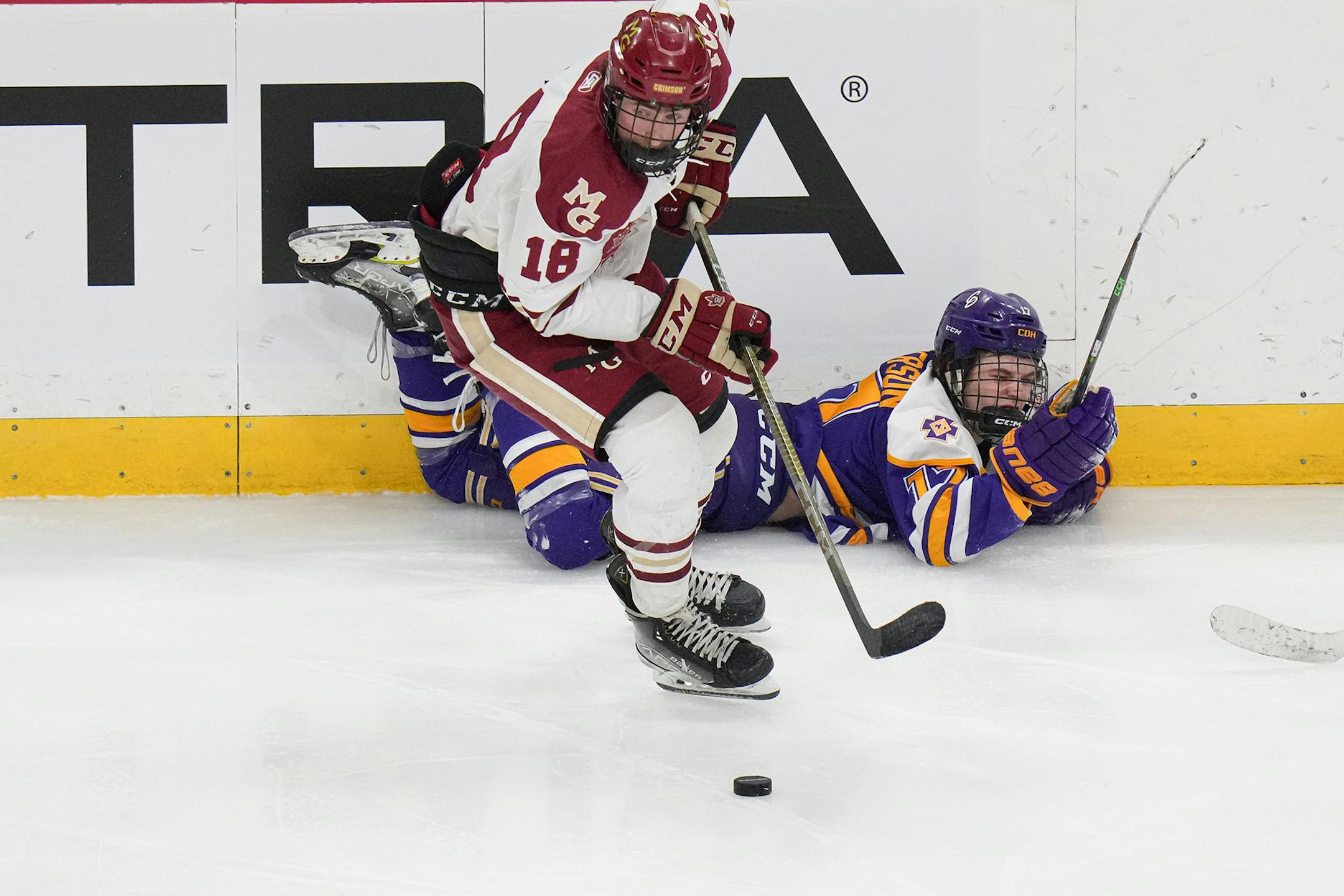 Maple Grove forward Blake Steenerson (18) grabs the puck as Cretin-Derham Hall forward Max Anderson (17) is agaijnst the boards in the third period.