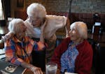Viva Froeming, left, touched the face of friend Virginia Goering as her twin sister Vera Sims looks on. The three ladies, all 101 years old, have been