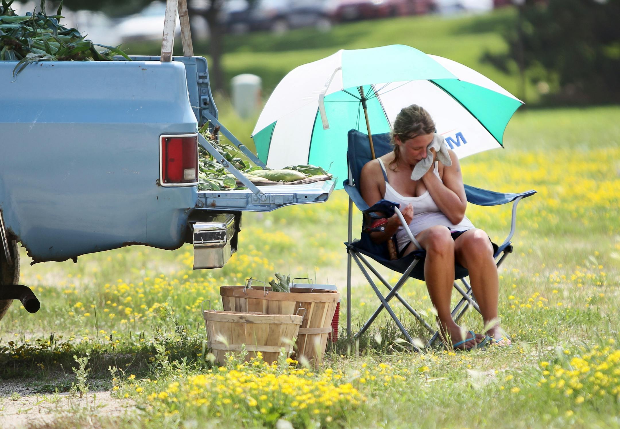 Tiffany Carrels of Lake City, Minn., wiped the sweat from her face with a towel as she sold sweet corn at the side of the road in Northfield as temperatures soared to 100 on July 18.