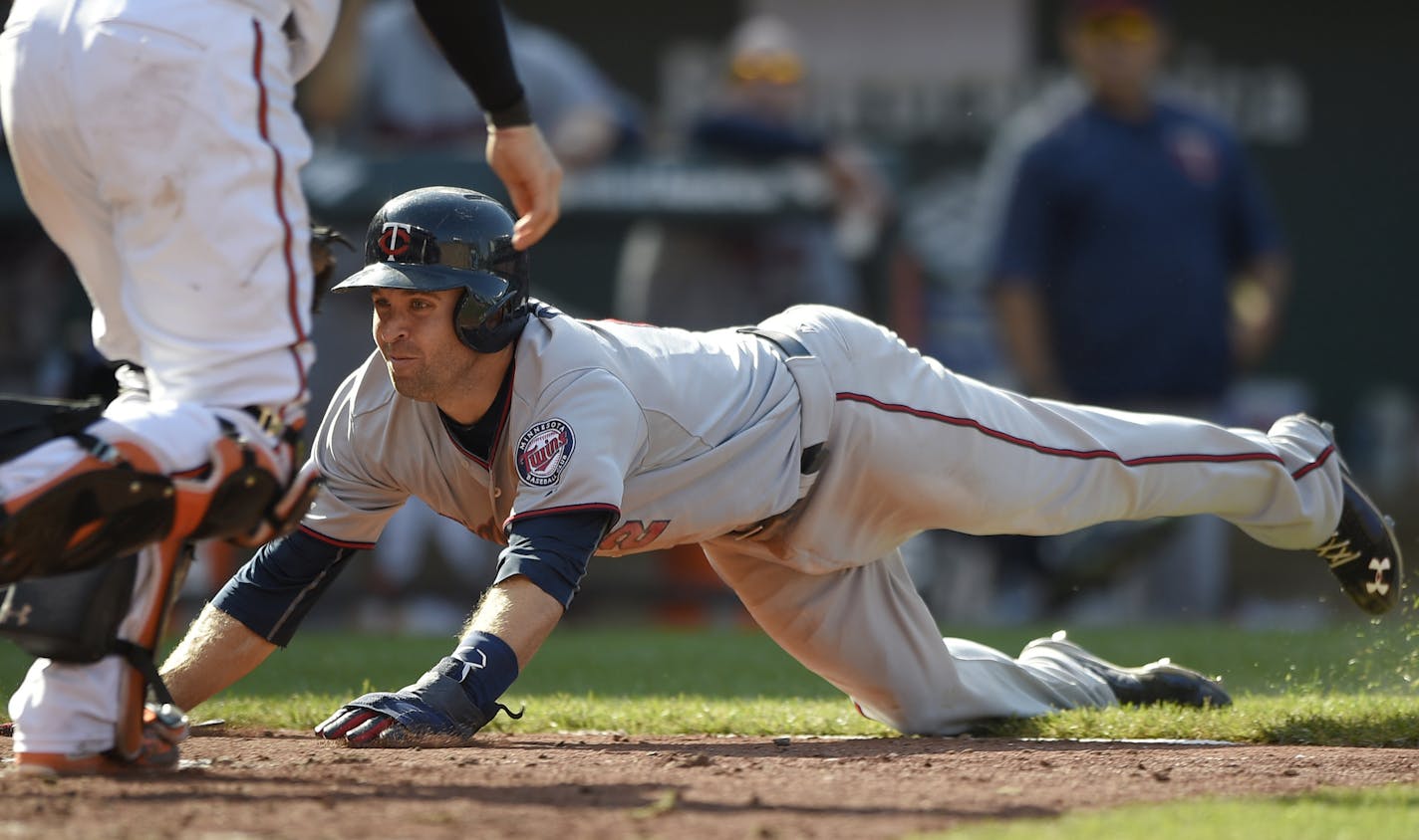 Minnesota Twins' Brian Dozier, right, slides home to score on a single by Trevor Plouffe as Baltimore Orioles catcher Caleb Joseph, left, waits for the ball during the ninth inning of a baseball game, Sunday, Aug. 23, 2015, in Baltimore. The Twins won 4-3 in 12 innings. (AP Photo/Nick Wass)