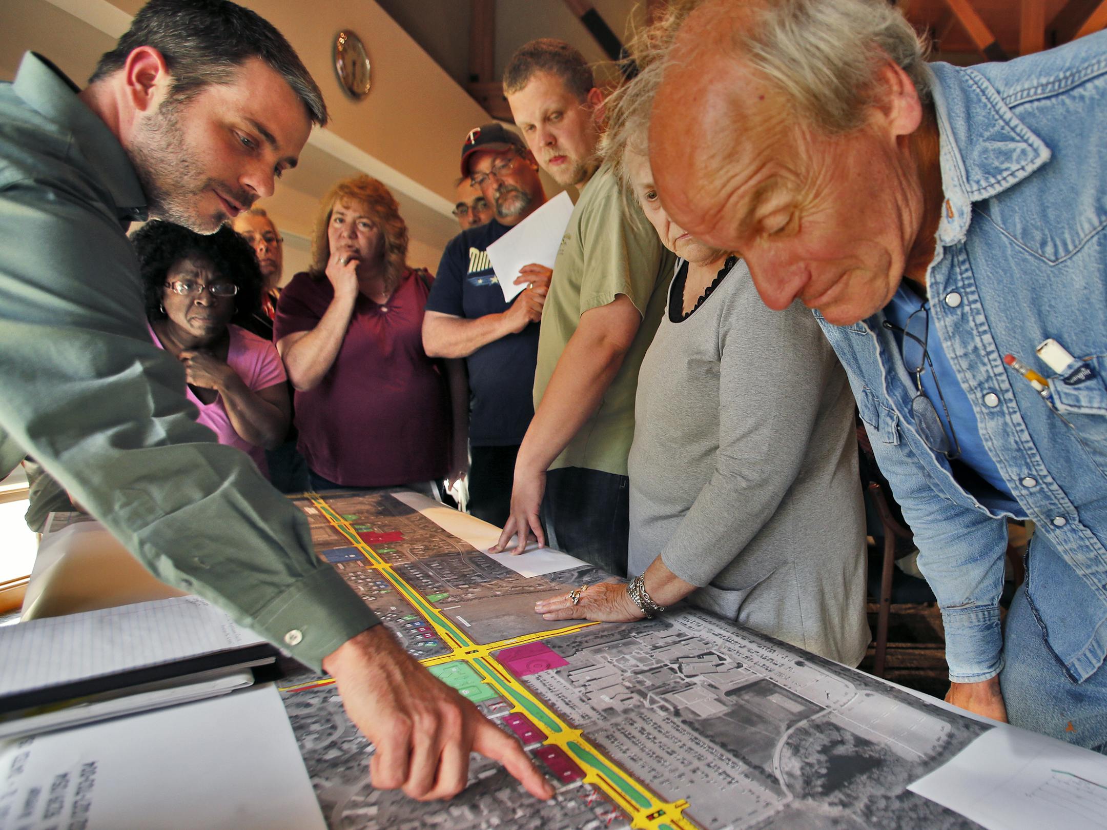 Hennepin County land acquisition manager Eric Drager, left, answered homeowners’ questions about the planned light-rail line as he referenced a detailed map to show the project’s proposed site during a meeting at Brooklyn Park City Hall last week.