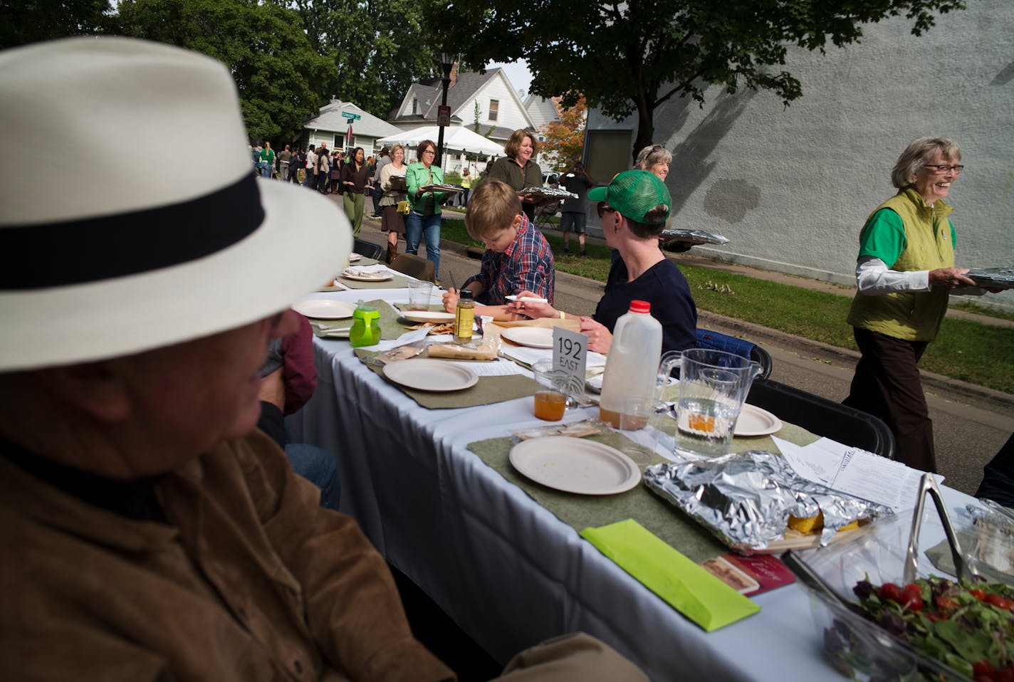 In the Frogtown neighborhood of St. Paul, Public Art Saint Paul and renowned Twin Cities artist Seitu Jones host the Community Meal by setting a half-mile long table along Victoria Street featuring locally grown produce from urban farms, which was served to some 2000 neighbors and invited guests A parade of hosts brought out the much-awaited chicken dish at the meal.