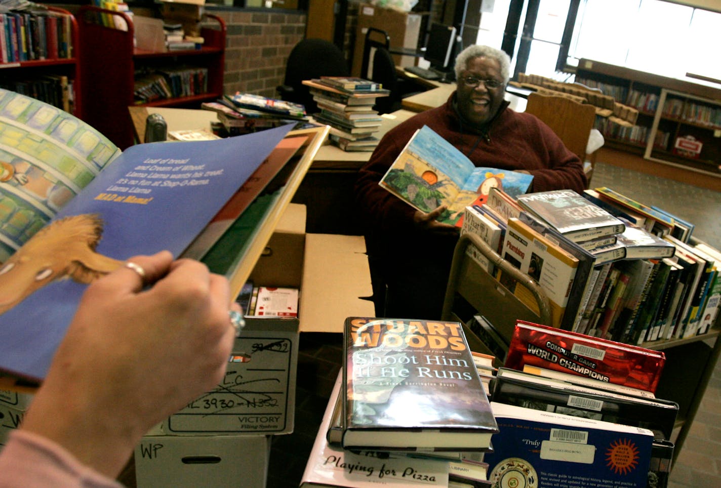 Jerry Blue, right, area manager for the North Minneapolis Library, and Ellen Buskirk, community librarian at Webber Park Library, enjoyed excerpts from books they unpacked to prepare for the reopening of Webber Park, slated for Jan. 3. Webber Park and other Minneapolis libraries were closed at the end of 2006 because of budget cuts.