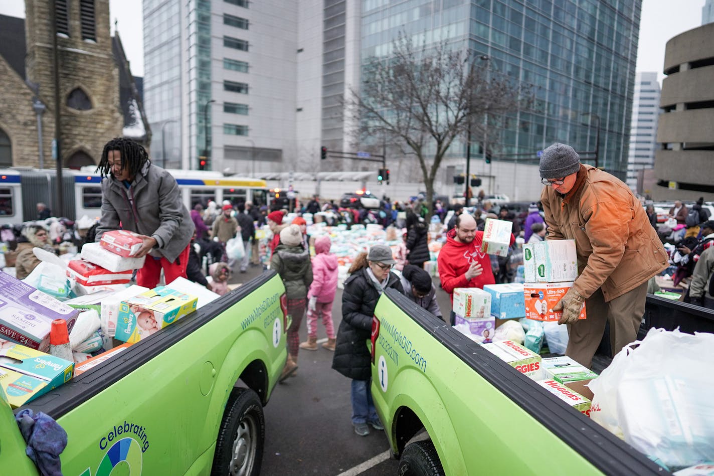 Volunteer Robert Hill of Minneapolis, left, helped load donations onto trucks as residents were bussed to temporary shelters. ] MARK VANCLEAVE ¥ Hundreds of people donated diapers, clothing and personal items after early morning fire tore through the Francis Drake Hotel apartments Wednesday, Dec. 25, 2019 in Minneapolis. The Francis Drake Hotel served as transitional housing for more than 200 people.