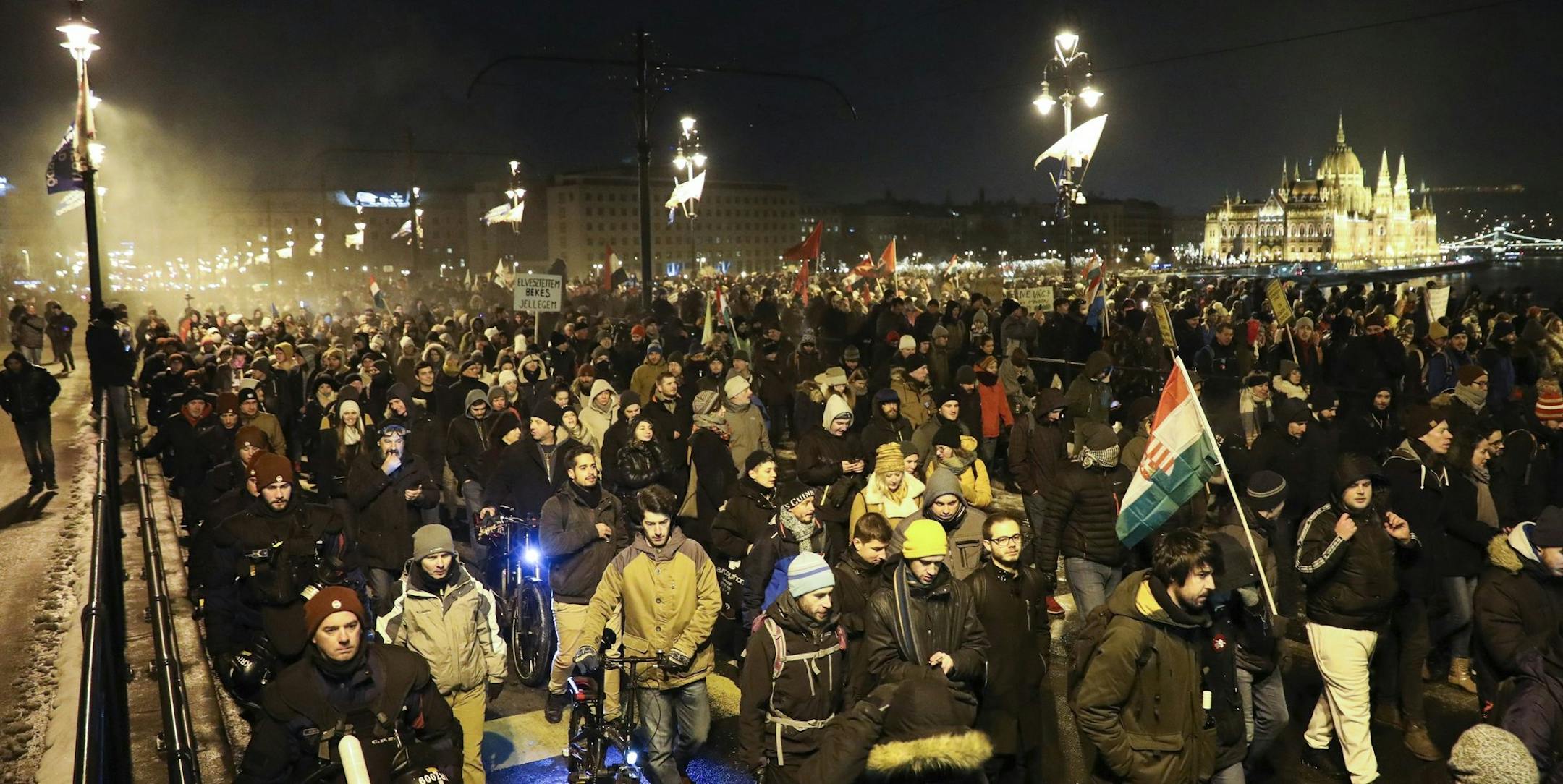 Anti-government demonstrators march across Margaret Bridge over the River Danube with the Parliament building in the background, in Budapest, Hungary, Sunday, Dec. 16, 2018. Protesters are demonstrating against recent changes to the labour laws. (Balazs Mohai/MTI via AP)