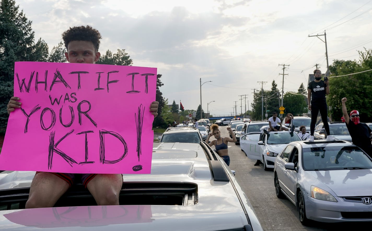 A protester sits on a car as they stop traffic Monday, Aug. 24, 2020, in Kenosha, Wis. Wisconsin Gov. Tony Evers has summoned the National Guard to head off another round of violent protests after the police shooting of a Black man turned Kenosha into the nation's latest flashpoint city in a summer of racial unrest. (AP Photo/Morry Gash)