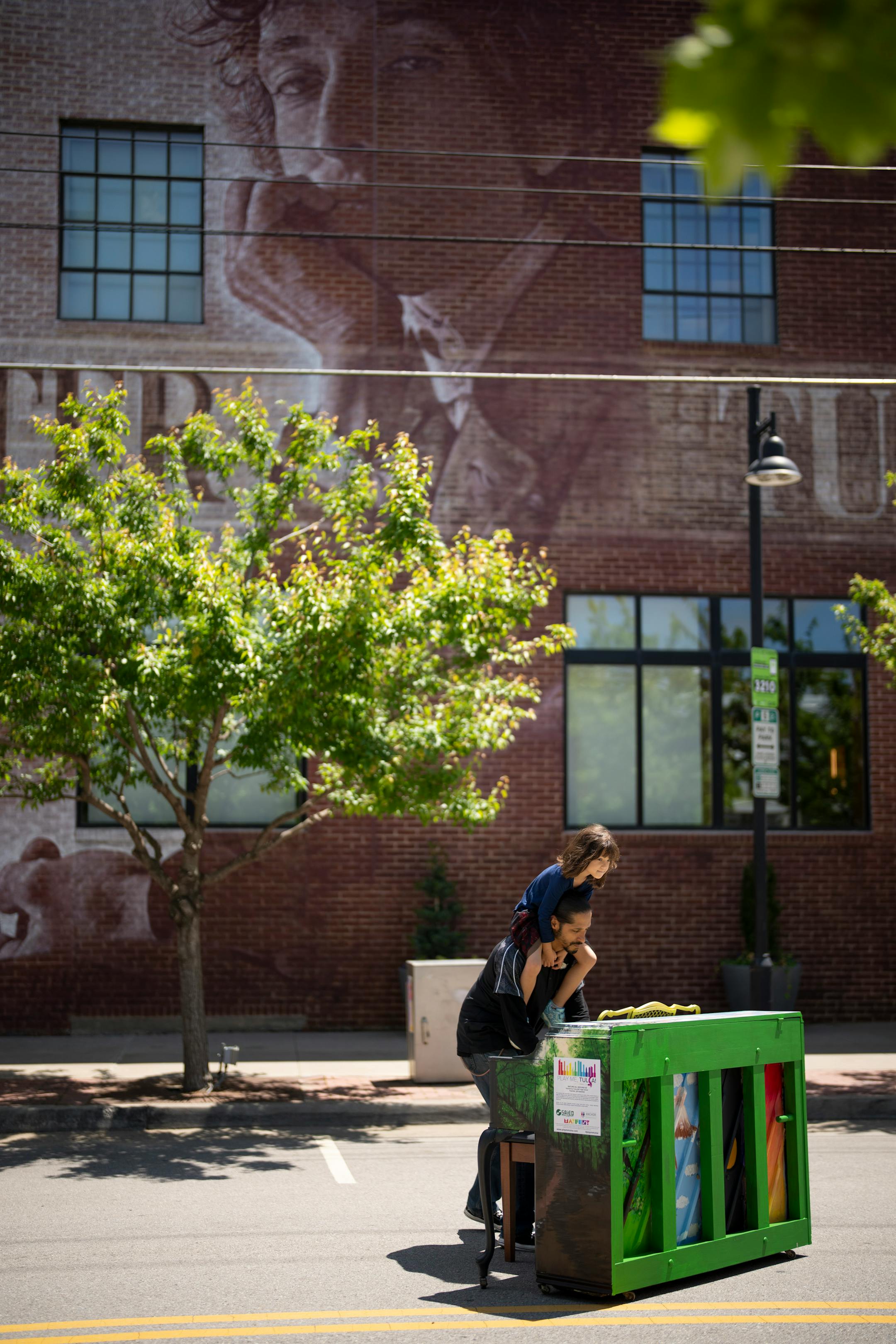 A father played one of several pianos outside the Bob Dylan Center, which features a mural based on a 1965 photograph by Jerry Schatzberg in Tulsa, Okla. on Friday, May 6, 2022. The pianos were a feature of Mayfest, Tulsa's annual arts festival.