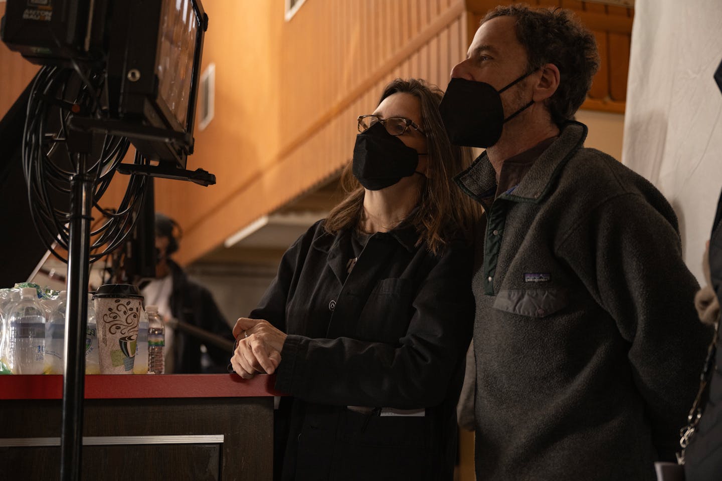 photograph of filmmakers Tricia Cooke and Ethan Coen, masked, on set