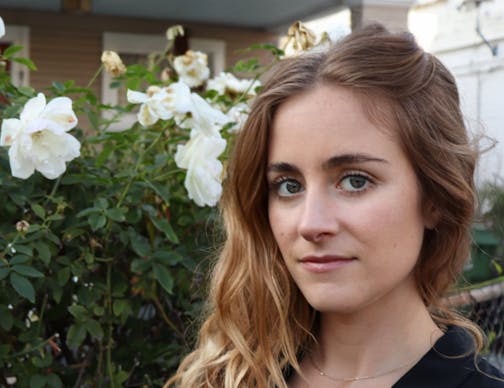 photo of writer Anna Dorn in front of a flowering bush