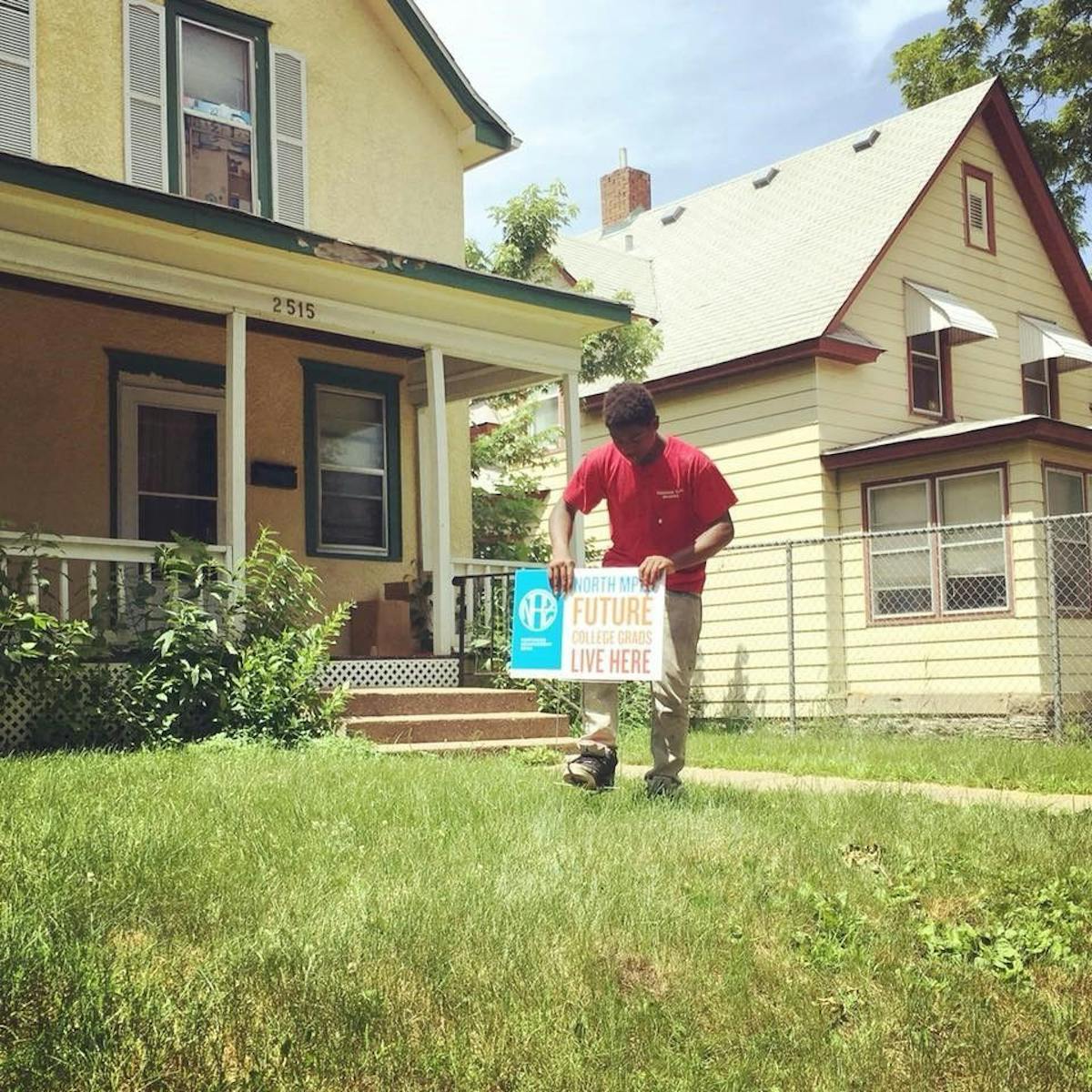 A young scholar places a sign in his yard of a North Minneapolis home. Five hundred "Future College Grads Live Here" signs went up in the neighborhood