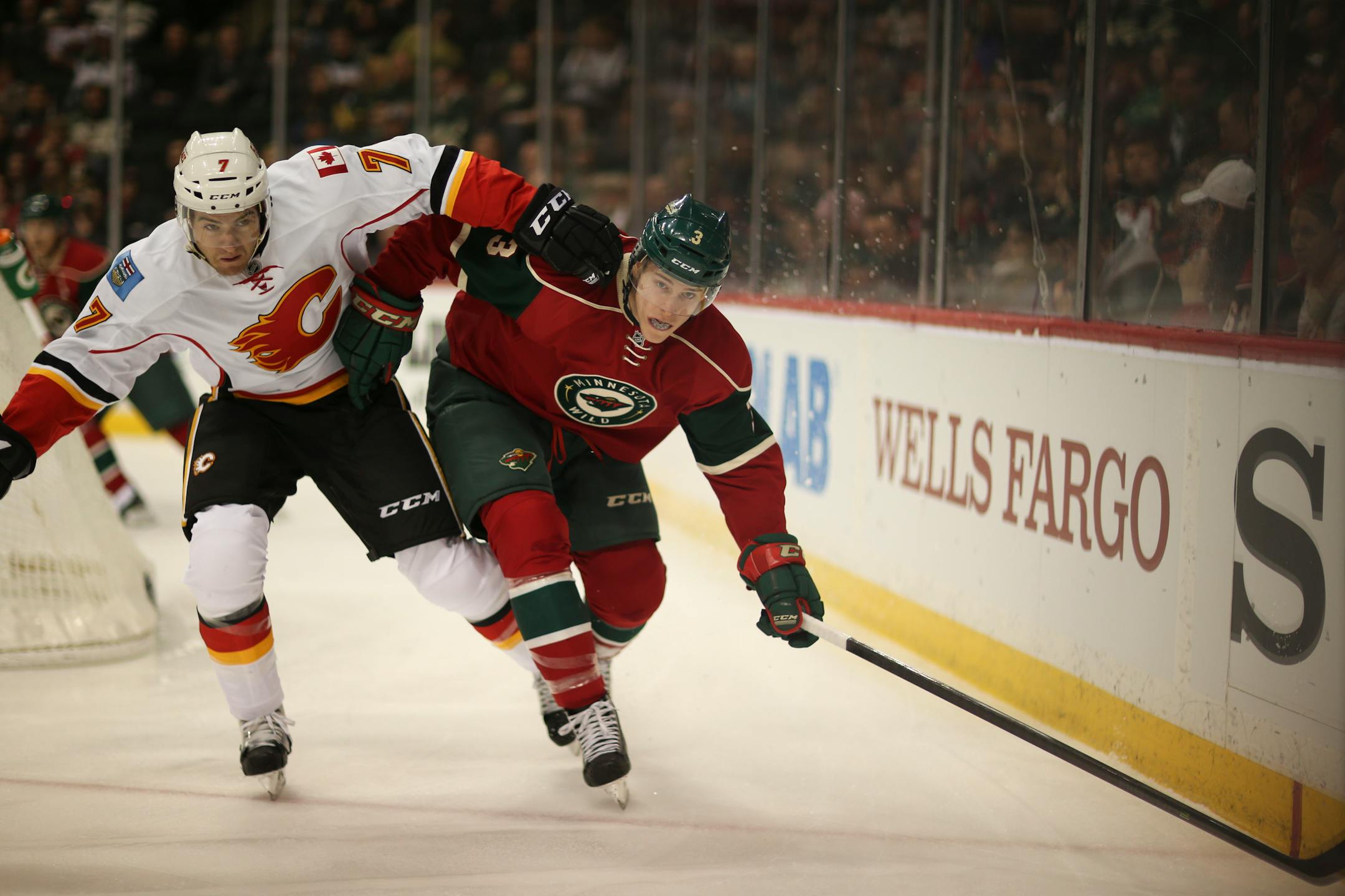 The Wild's Charlie Coyle and Calgary's T.J. Brodie kept their eyes on the puck as they followed it into the corner in the first period.