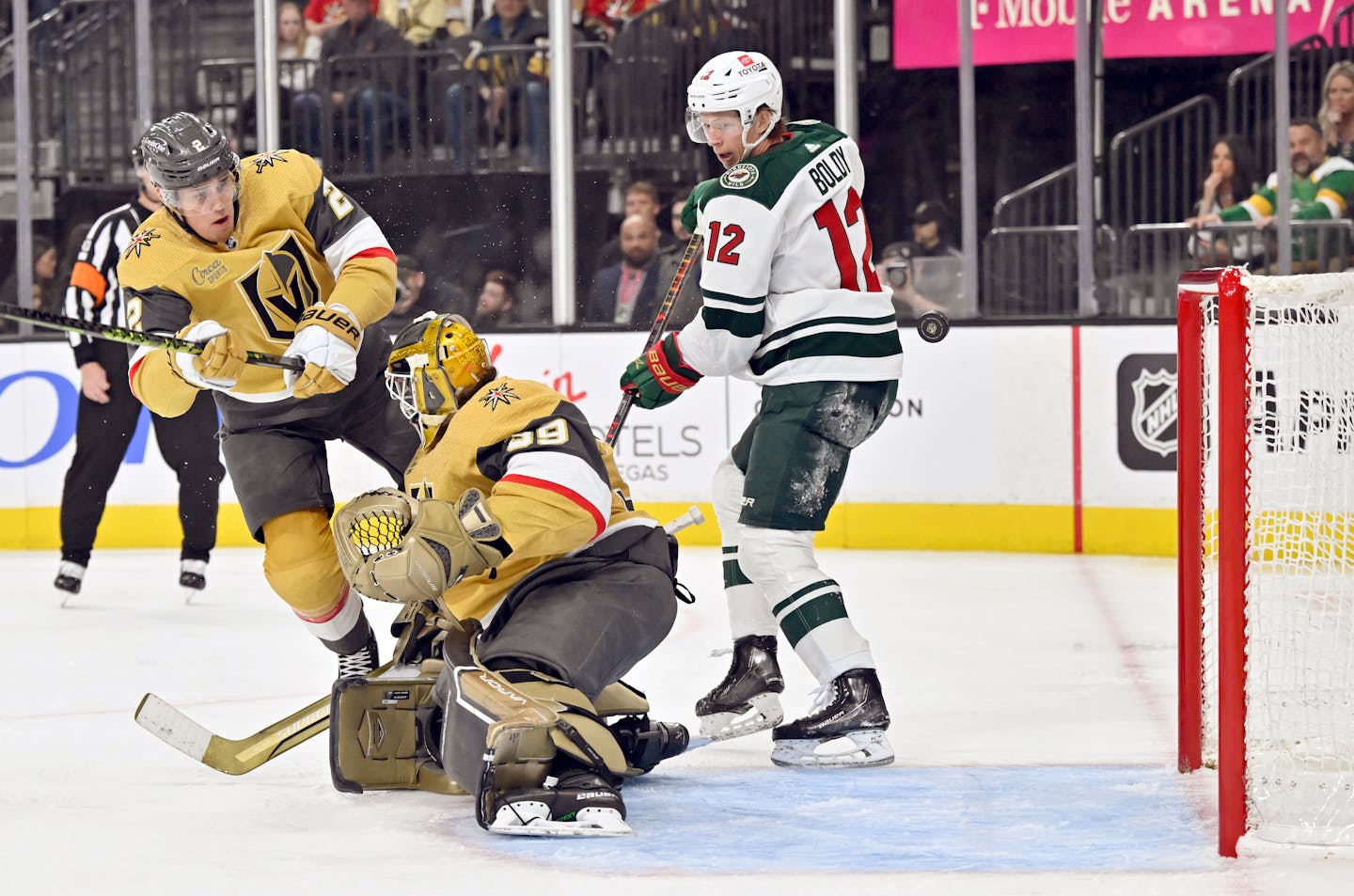 Minnesota Wild left wing Matt Boldy (12) looks on as he scores a goal against Vegas Golden Knights goaltender Laurent Brossoit (39) and defenseman Zach Whitecloud (2) during the first period of an NHL hockey game Saturday, April 1, 2023, in Las Vegas. (AP Photo/David Becker)