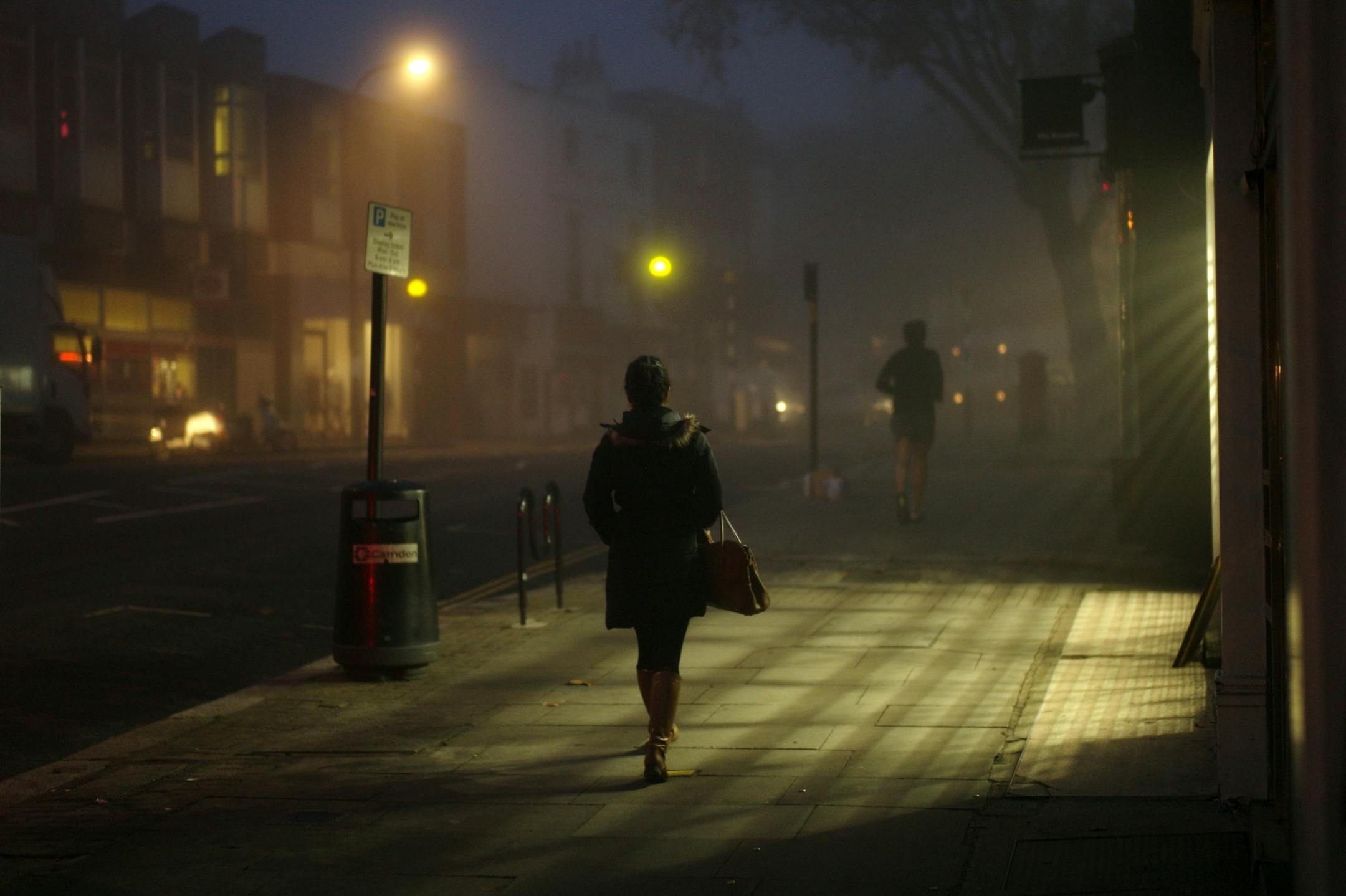 A woman and a jogger move through misty conditions along Hampstead High Street in north London, Wednesday, Nov. 23, 2011.